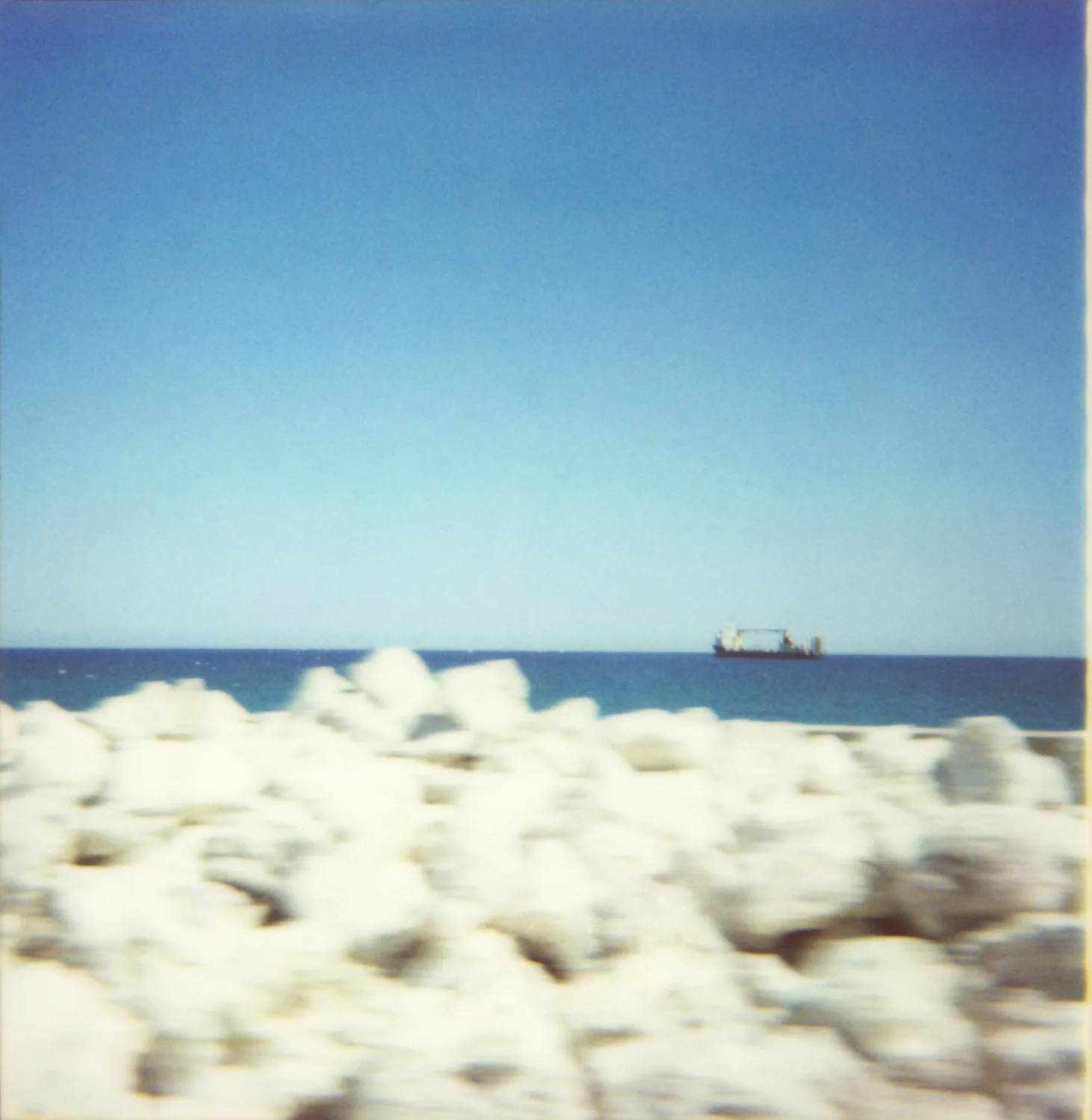 Ship on the horizon behind blurred white rocks — Expired Polaroids in Florida, fine art and analog photography by Janina Laszlo