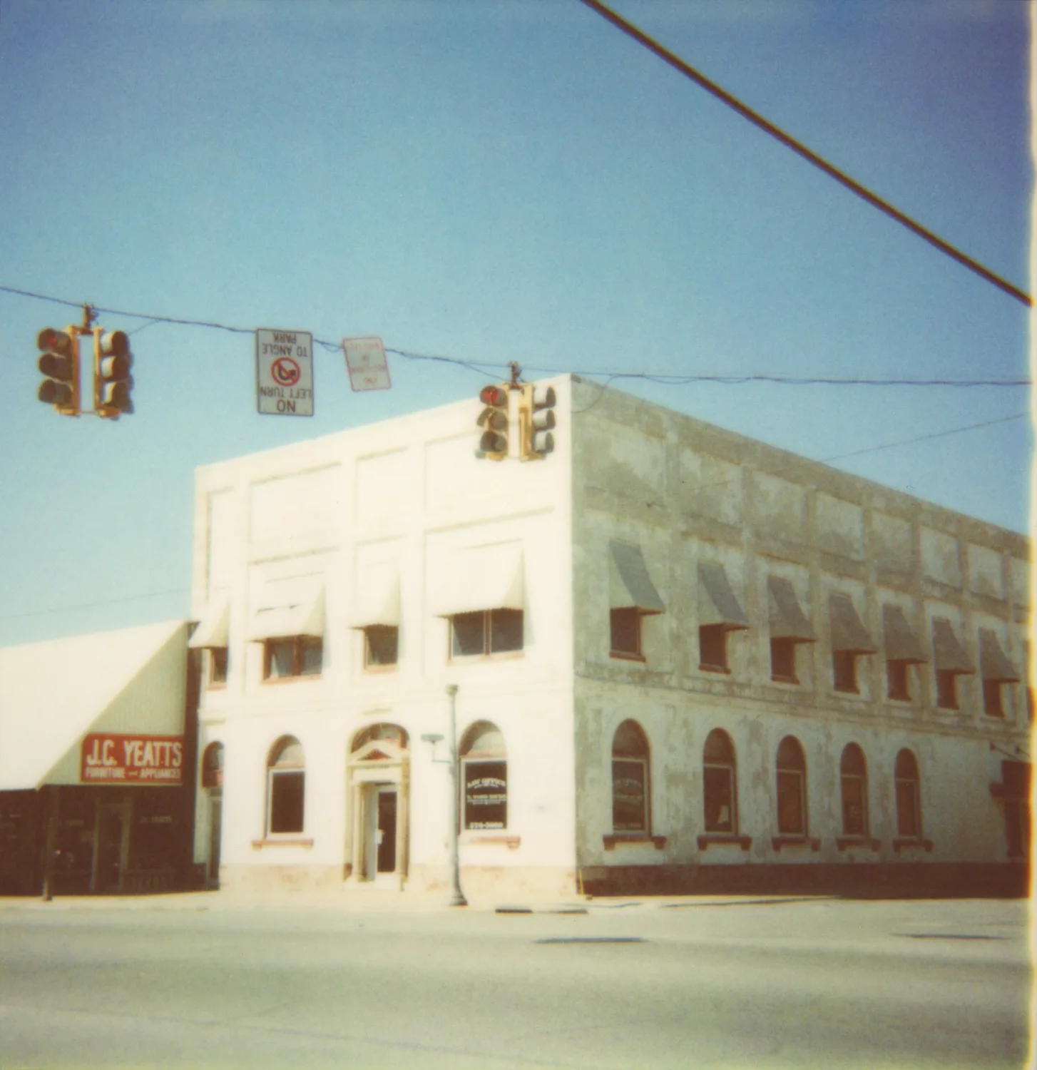White corner building with traffic lights and J.C. Yeatts sign — Expired Polaroids in Florida, fine art and analog photography by Janina Laszlo