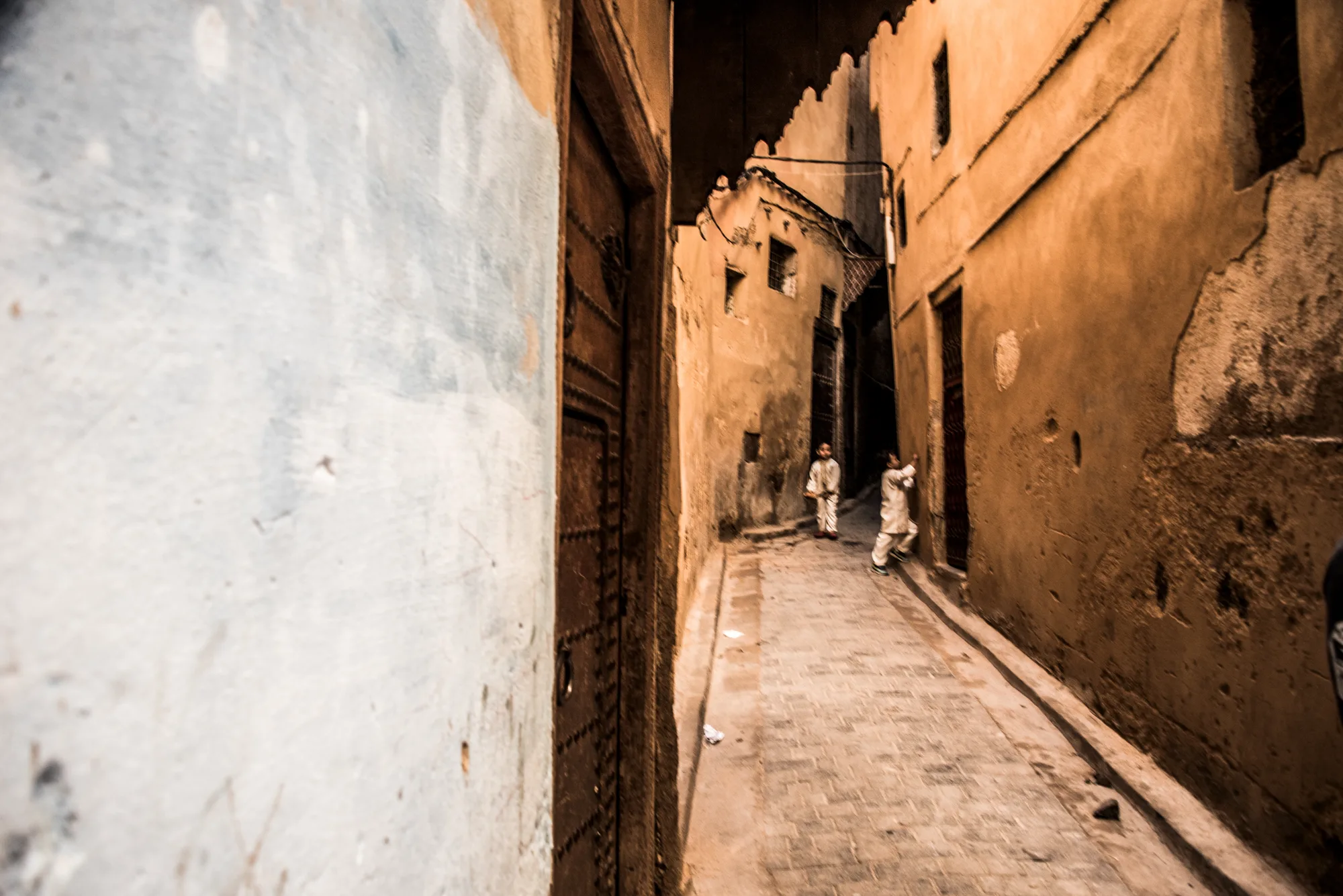 Two boys in white robes in a narrow ochre alley, Fez medina — Fez, street and travel photography by Janina Laszlo