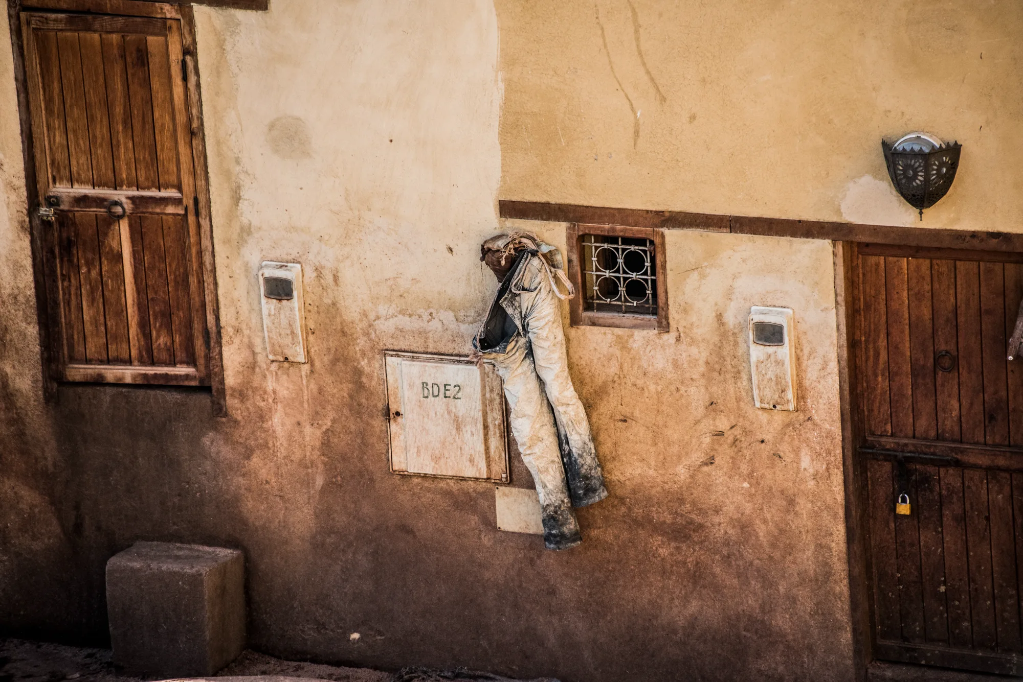Work trousers hung on an ochre wall between wooden doors, Fez — Fez, street and travel photography by Janina Laszlo