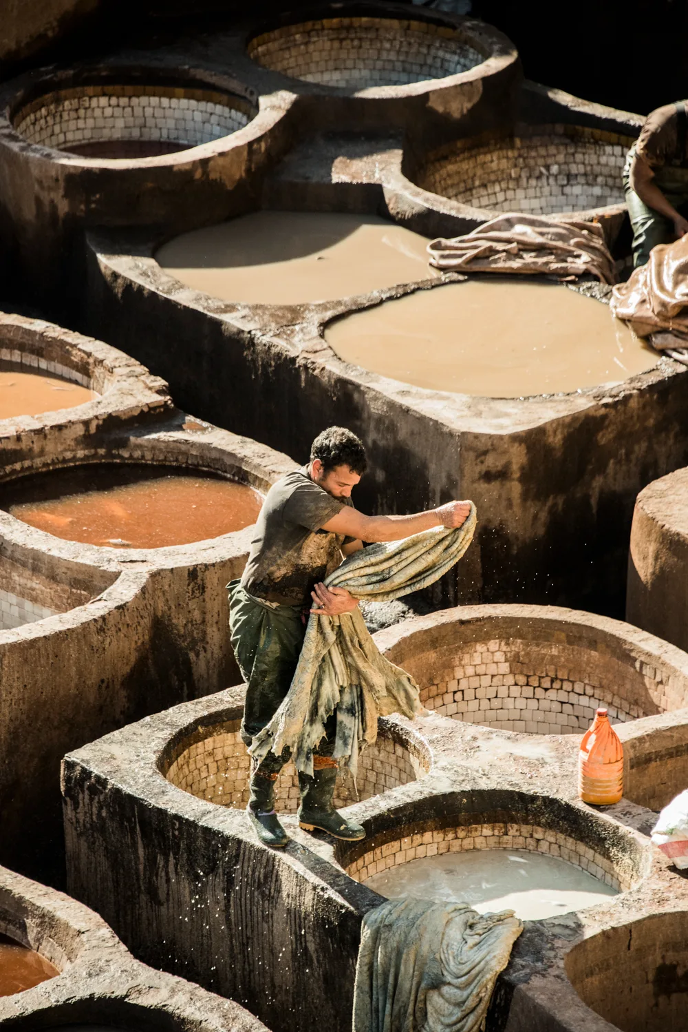 Tanner wringing out a hide above the stone vats, Chouara Tannery, Fez — Fez, street and travel photography by Janina Laszlo