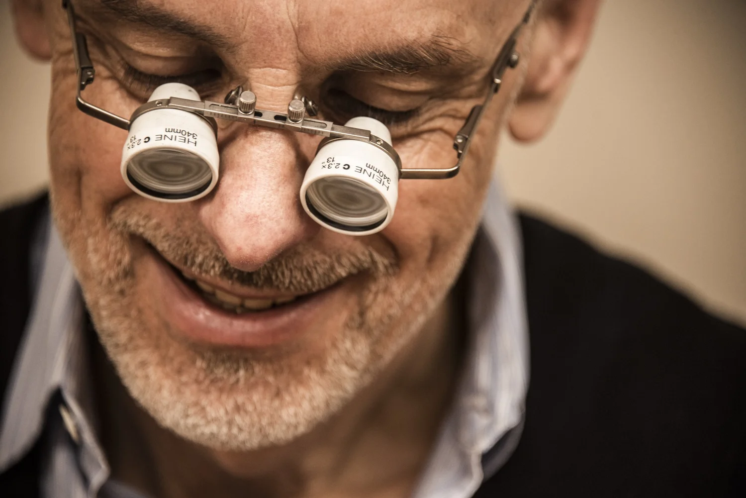 Smiling goldsmith Gerd Weickmann wearing binocular loupes in his workshop — reportage by Janina Laszlo, photographer in Munich
