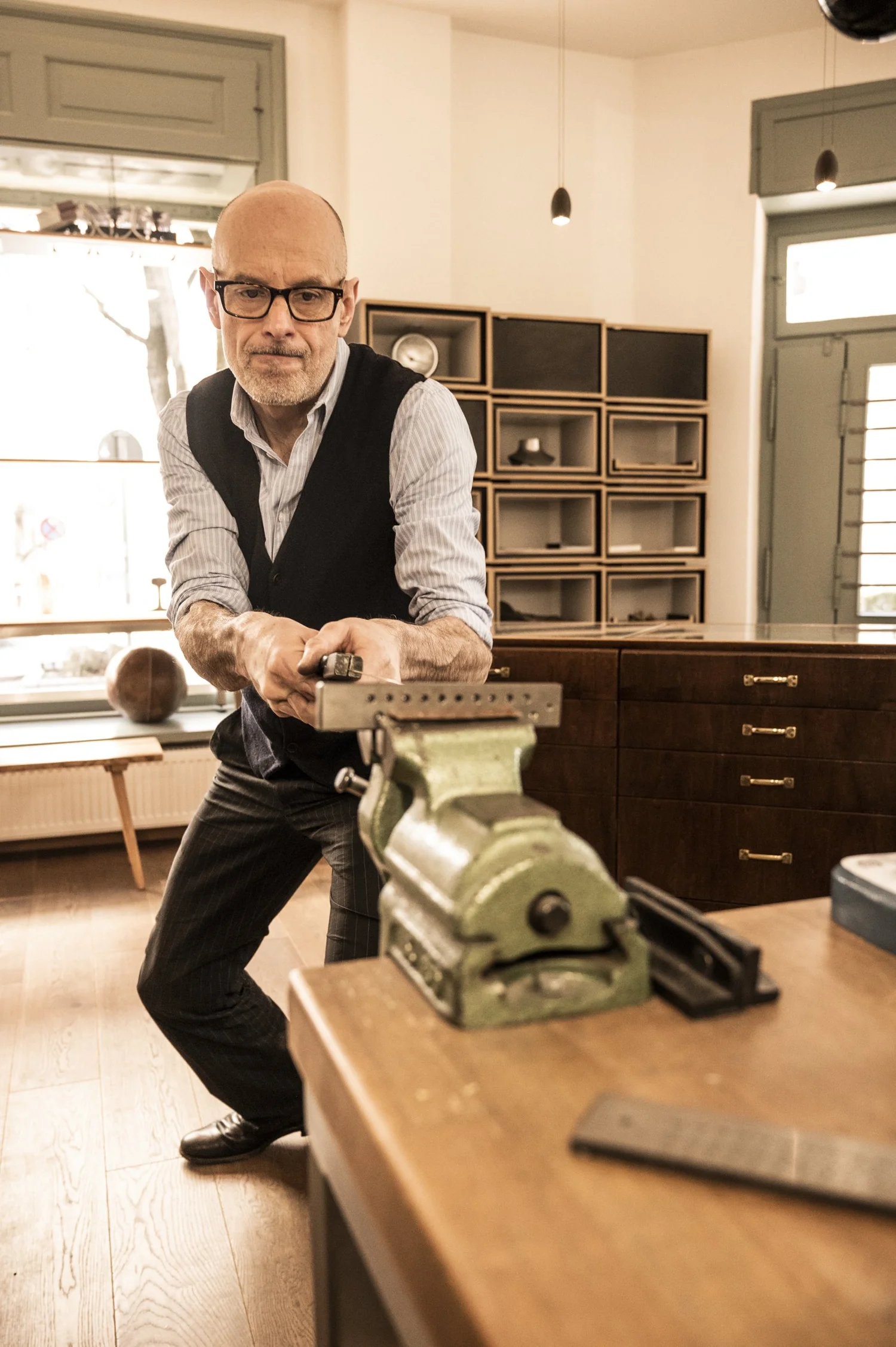 Gerd Weickmann working a rolling mill in his bright goldsmith workshop — reportage by Janina Laszlo, photographer in Munich