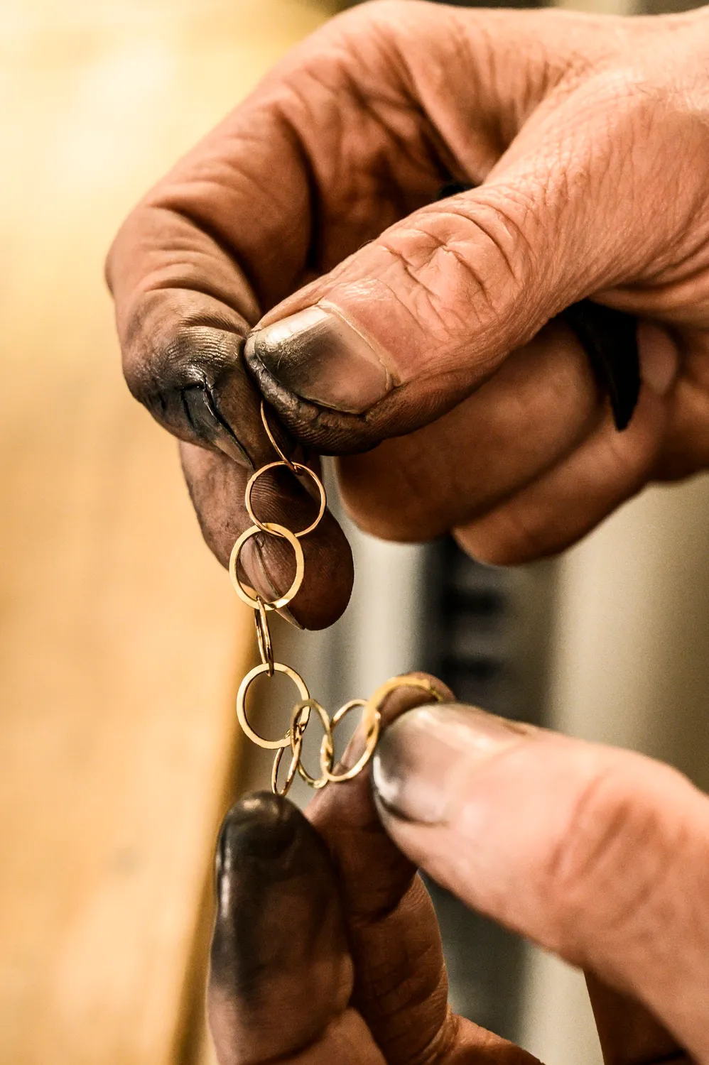 Blackened fingertips holding a delicate gold chain — goldsmith Gerd Weickmann — reportage by Janina Laszlo, photographer in Munich