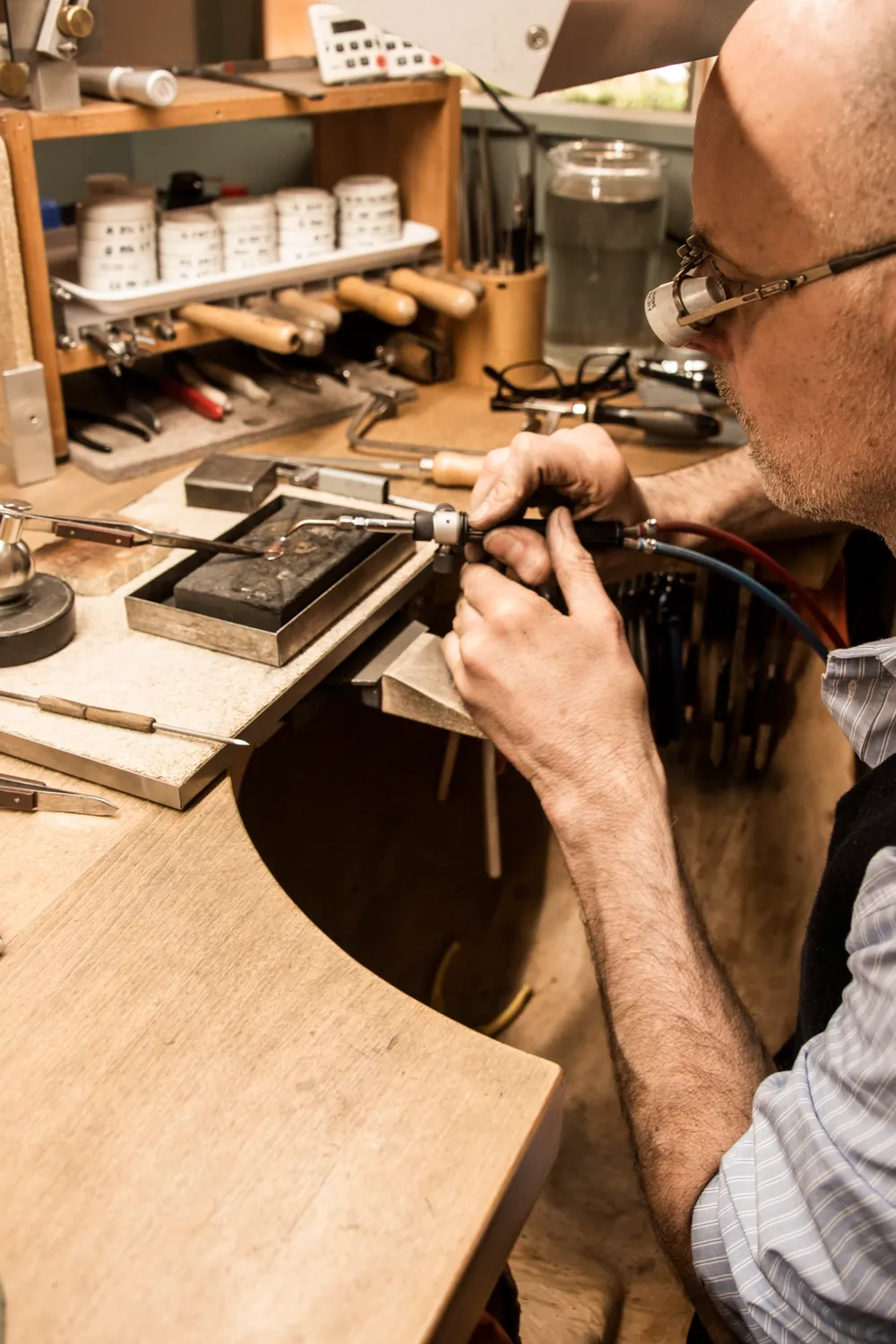 Gerd Weickmann bent over his bench among jars and tools — goldsmith Gerd Weickmann — reportage by Janina Laszlo, photographer in Munich