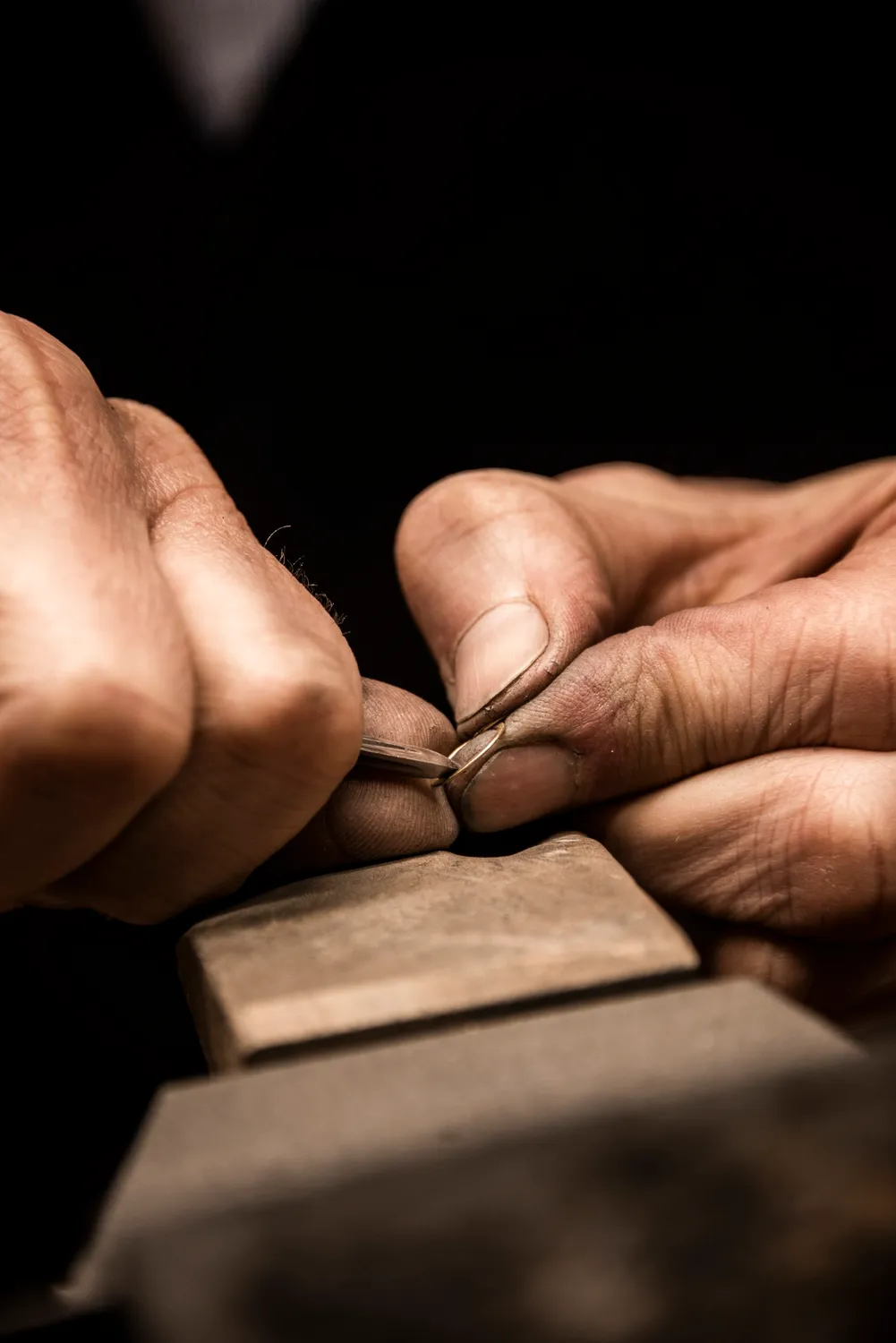 Hands filing a small piece of jewellery on a wooden bench pin — goldsmith Gerd Weickmann — reportage by Janina Laszlo, photographer in Munich