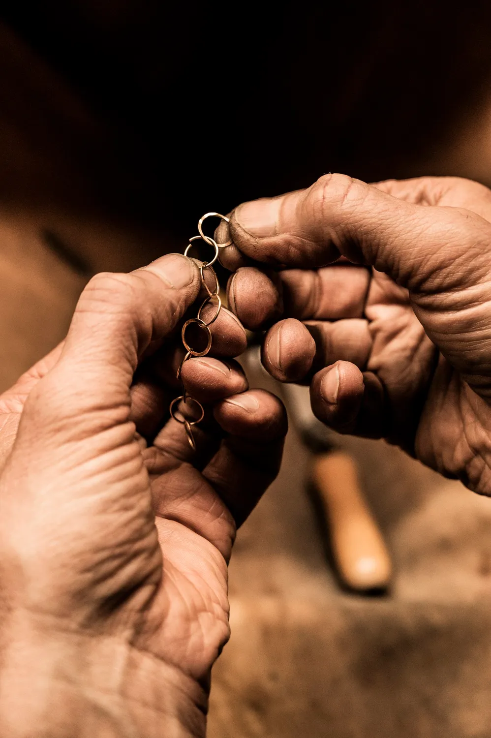 Hands threading a fine chain in warm low light — goldsmith Gerd Weickmann — reportage by Janina Laszlo, photographer in Munich