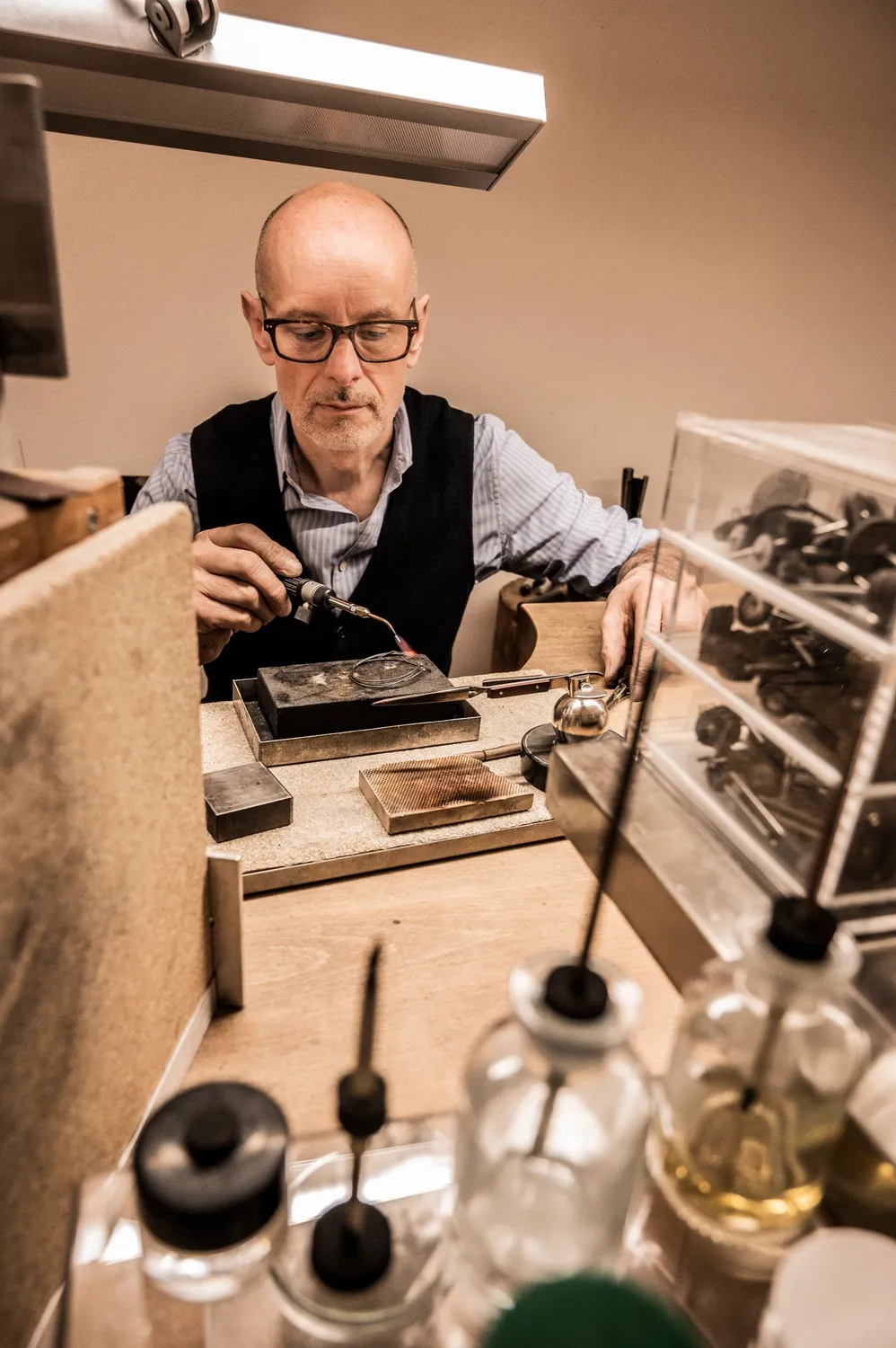 Goldsmith at his bench with bottles and burners in the foreground — goldsmith Gerd Weickmann — reportage by Janina Laszlo, photographer in Munich