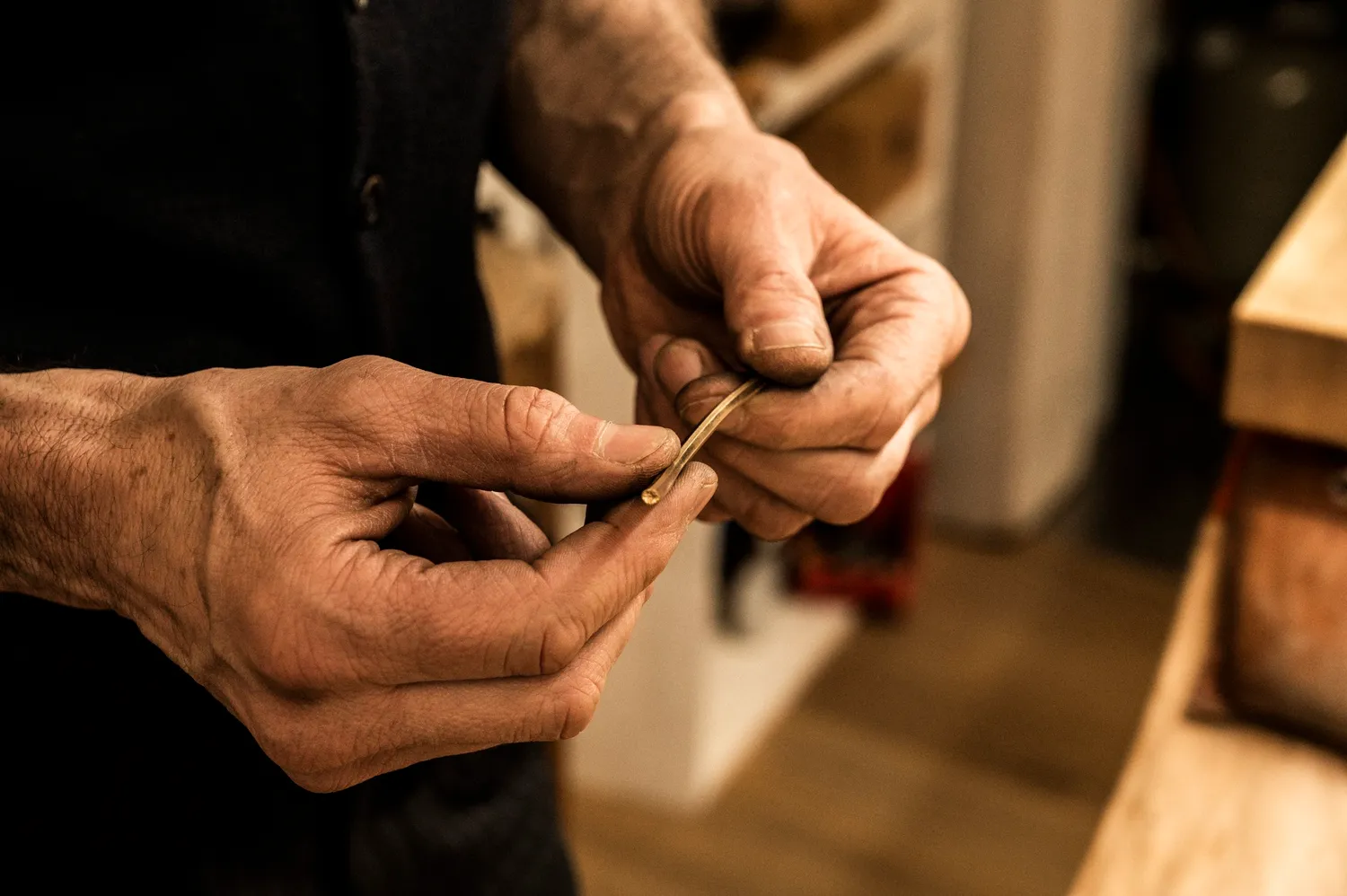 Hands shaping a thin gold band against a dark background — goldsmith Gerd Weickmann — reportage by Janina Laszlo, photographer in Munich