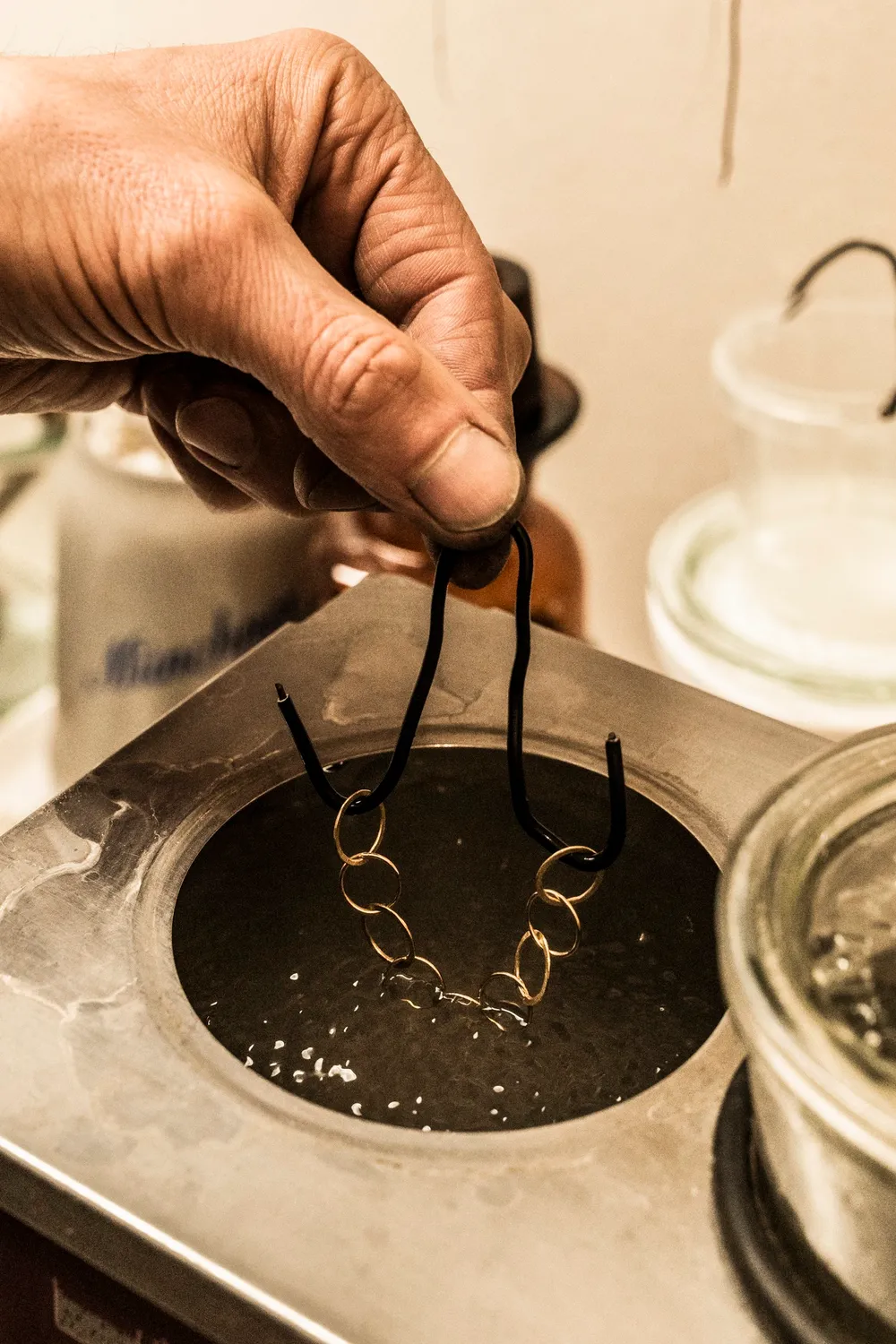 Hand lifting jewellery out of a pickling bath with tweezers — goldsmith Gerd Weickmann — reportage by Janina Laszlo, photographer in Munich