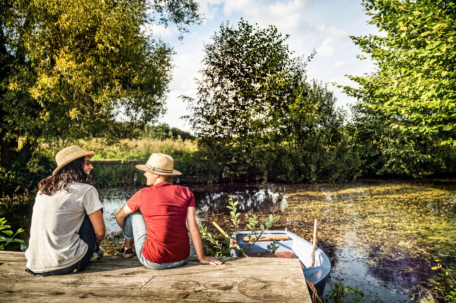 Two women in straw hats laughing on a jetty during a cycling break on the Hop Route — editorial travel photography for a Bavarian tourism campaign by Janina Laszlo