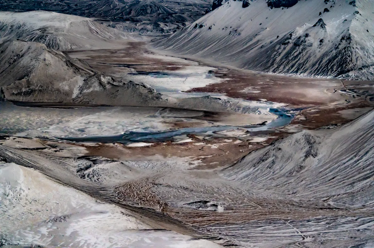 Aerial view of snow-dusted mountains around a glacial river valley, Ofanfrá series — travel photography by Janina Laszlo