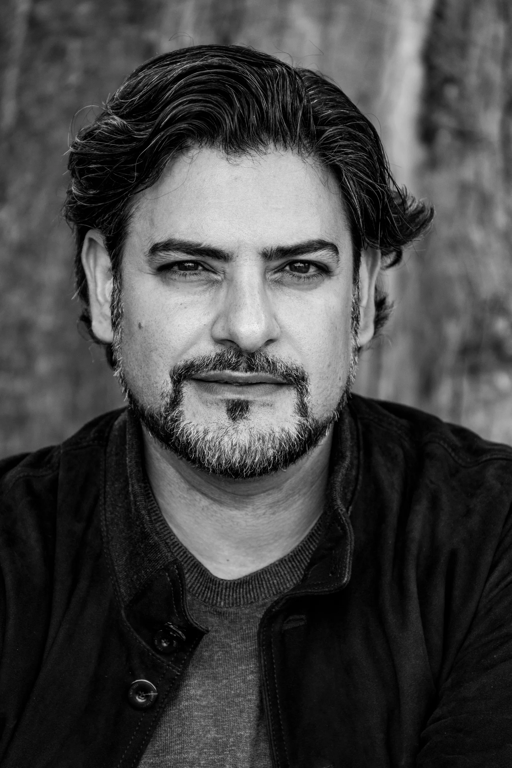 Black-and-white close-up of Ilker Arcayürek with dark wavy hair and beard — Ilker Arcayürek, artist portrait photography by Janina Laszlo
