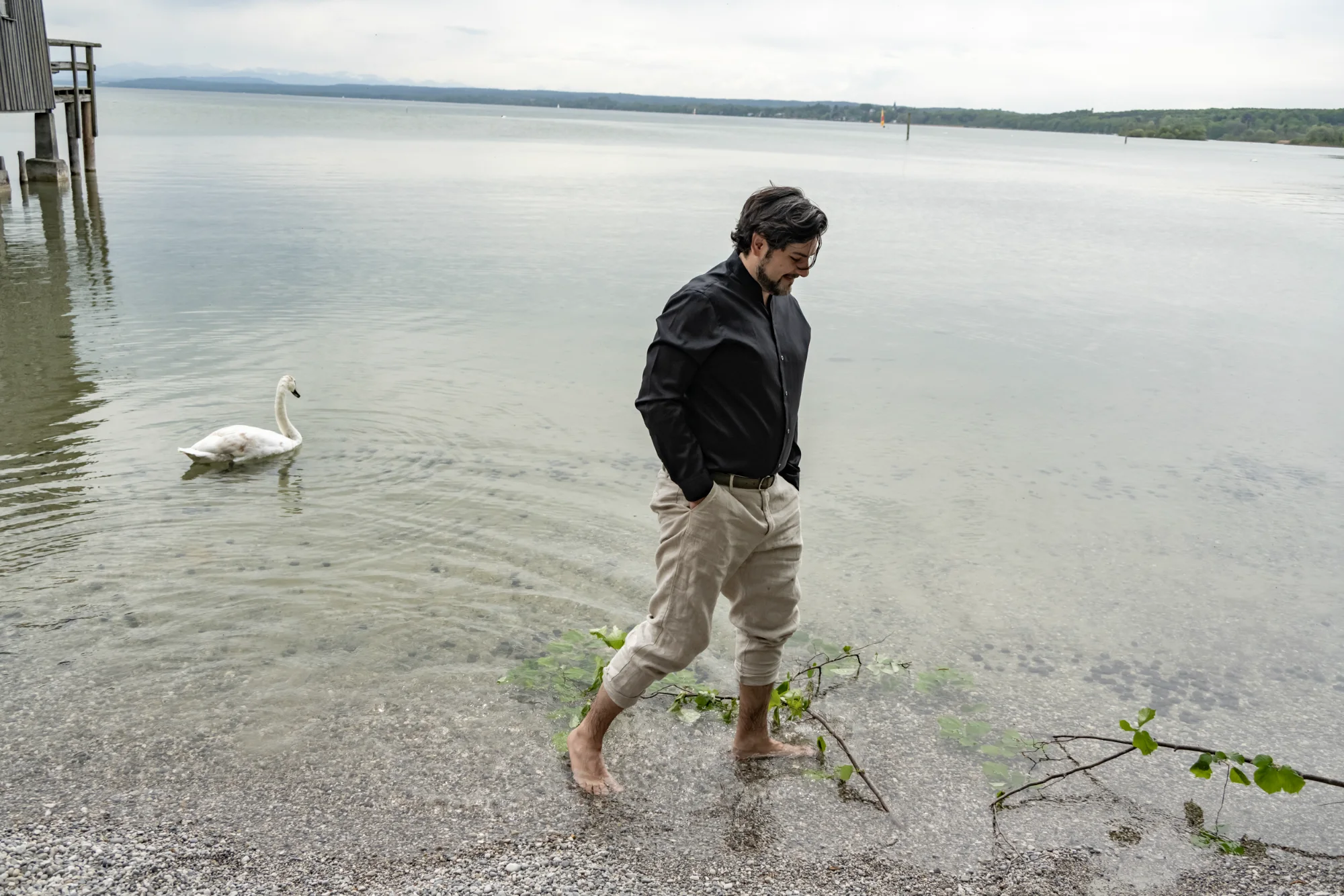 Ilker Arcayürek wading barefoot in the lake next to a swan — Ilker Arcayürek, artist portrait photography by Janina Laszlo