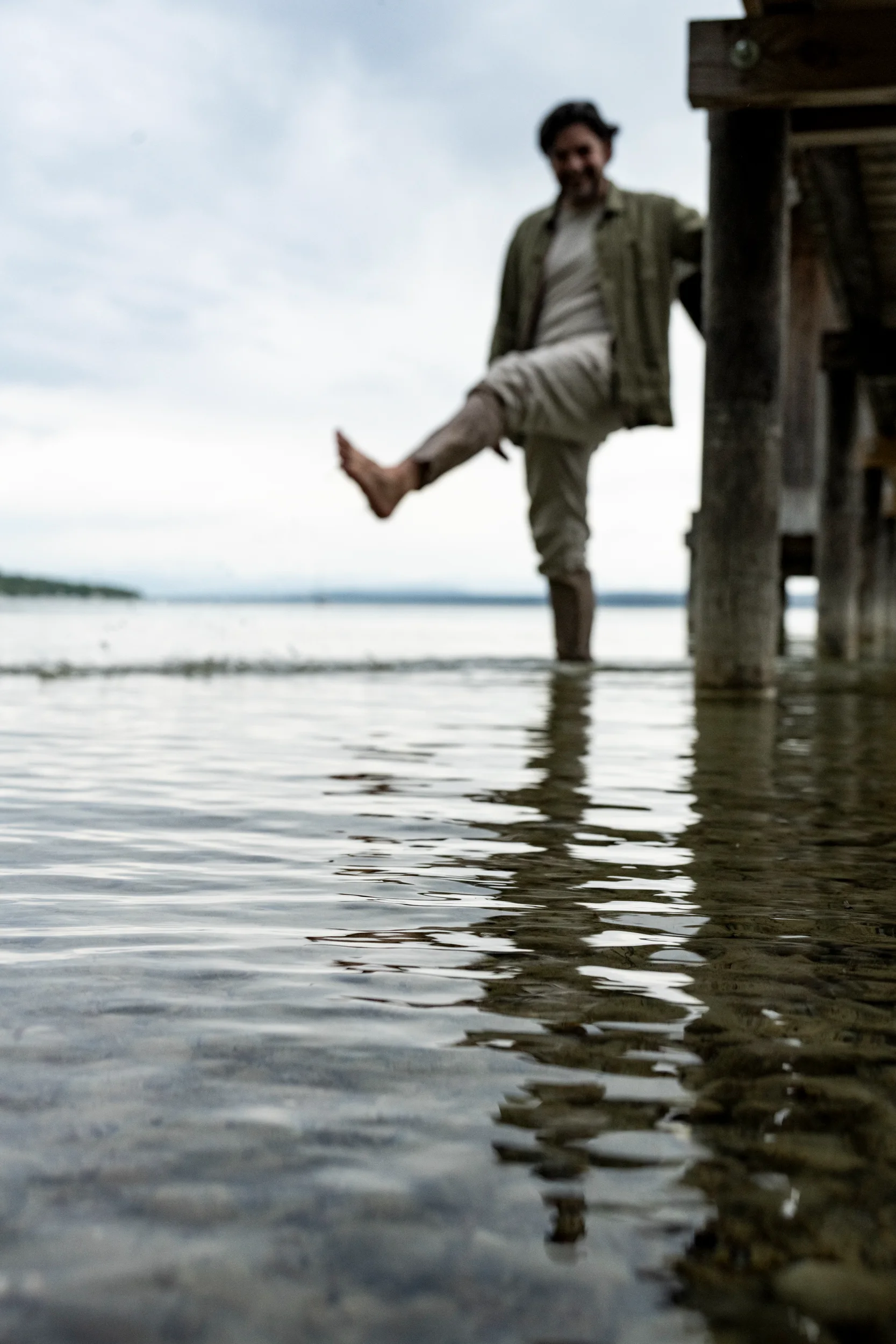Ilker Arcayürek kicking water beside a jetty, low angle across the surface — Ilker Arcayürek, artist portrait photography by Janina Laszlo