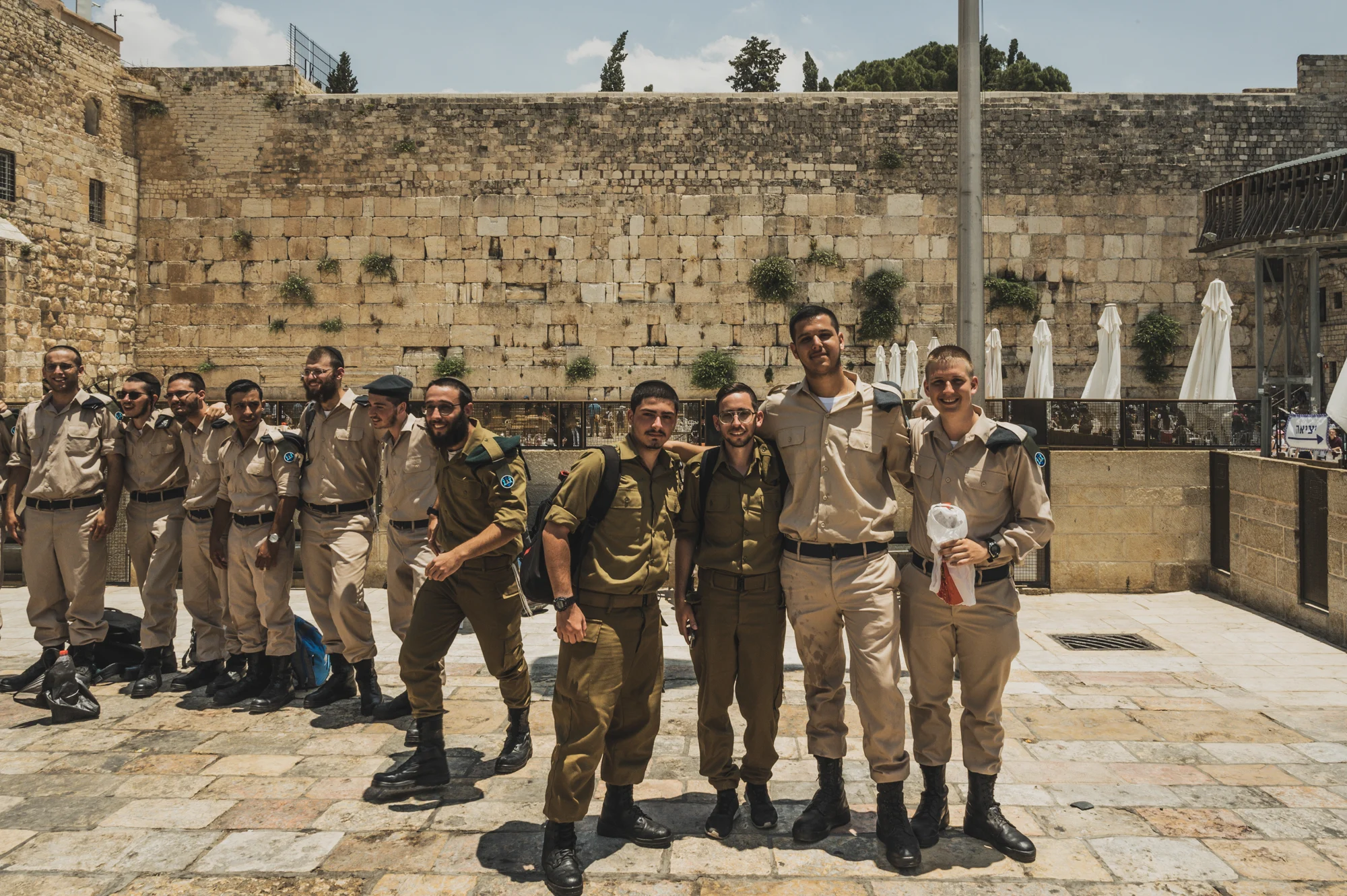 Young Israeli soldiers in uniform posing arm in arm in front of the Western Wall, Jerusalem — Israel, travel and street photography by Janina Laszlo