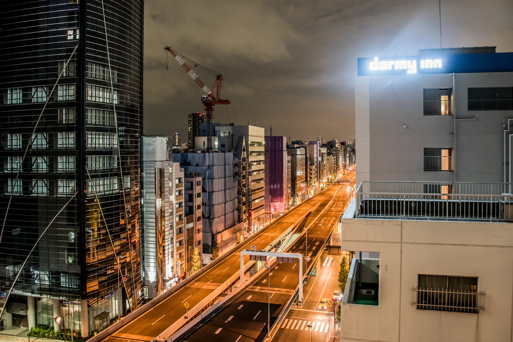 Elevated expressway glowing orange at night beside a Dormy Inn sign, Tokyo — Japan, travel and street photography by Janina Laszlo