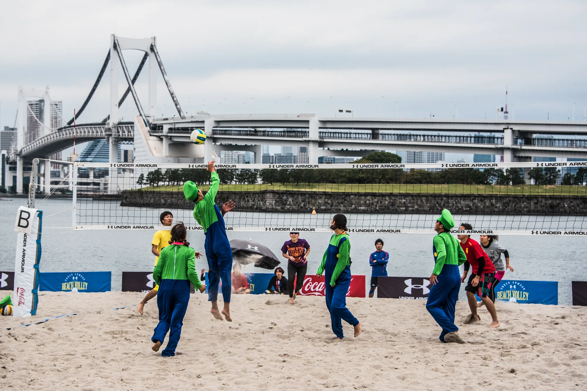 Beach volleyball players in costumes in front of the Rainbow Bridge, Odaiba, Tokyo — Japan, travel and street photography by Janina Laszlo