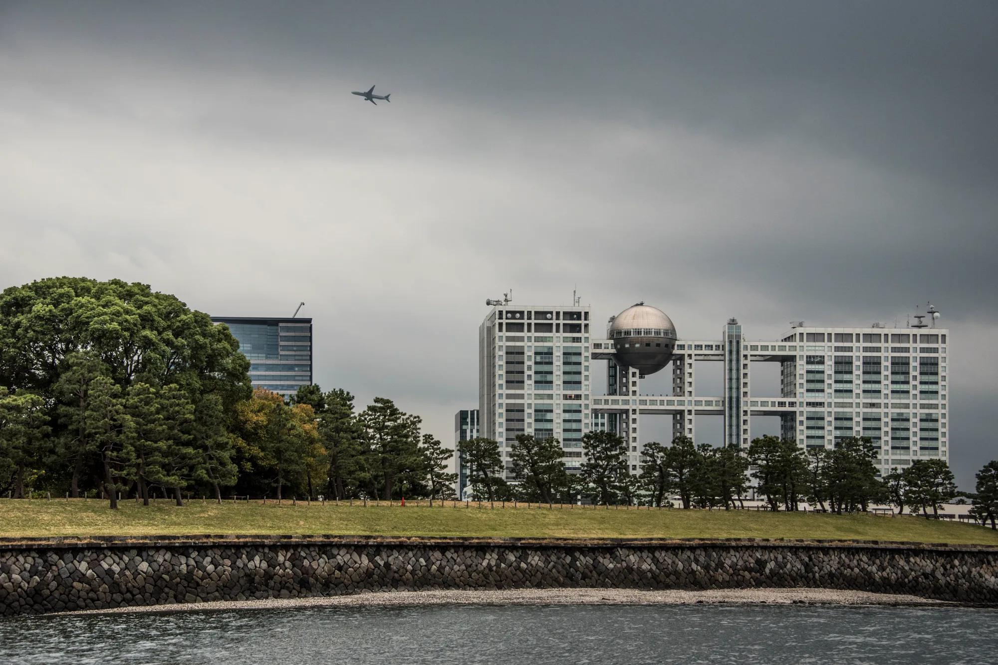 Fuji TV building with its sphere and a plane overhead, Odaiba, Tokyo — Japan, travel and street photography by Janina Laszlo
