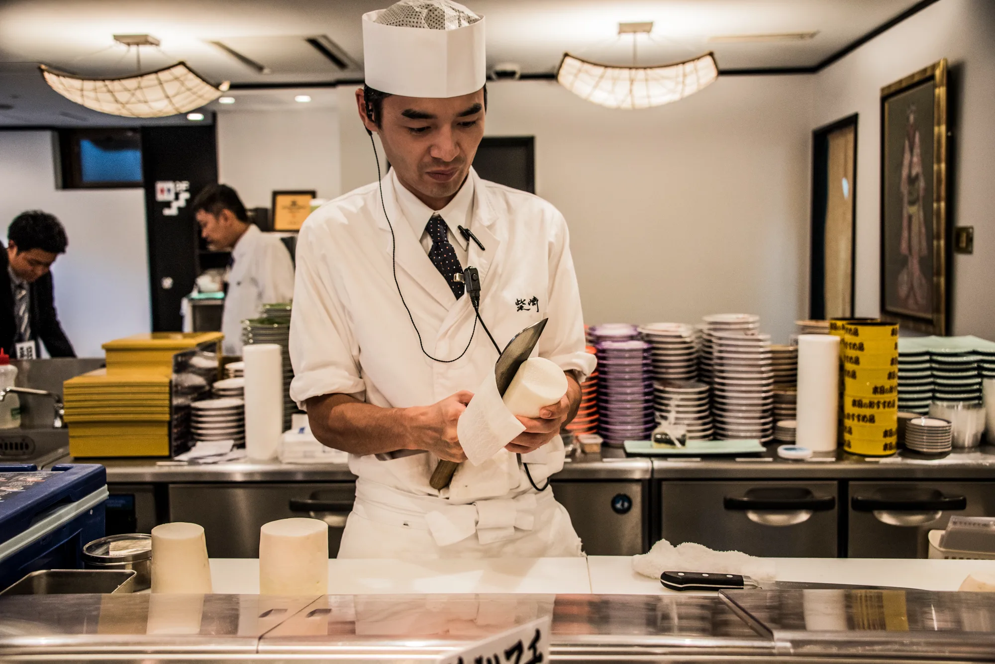 Sushi chef peeling daikon at a counter of stacked plates, Japan — Japan, travel and street photography by Janina Laszlo