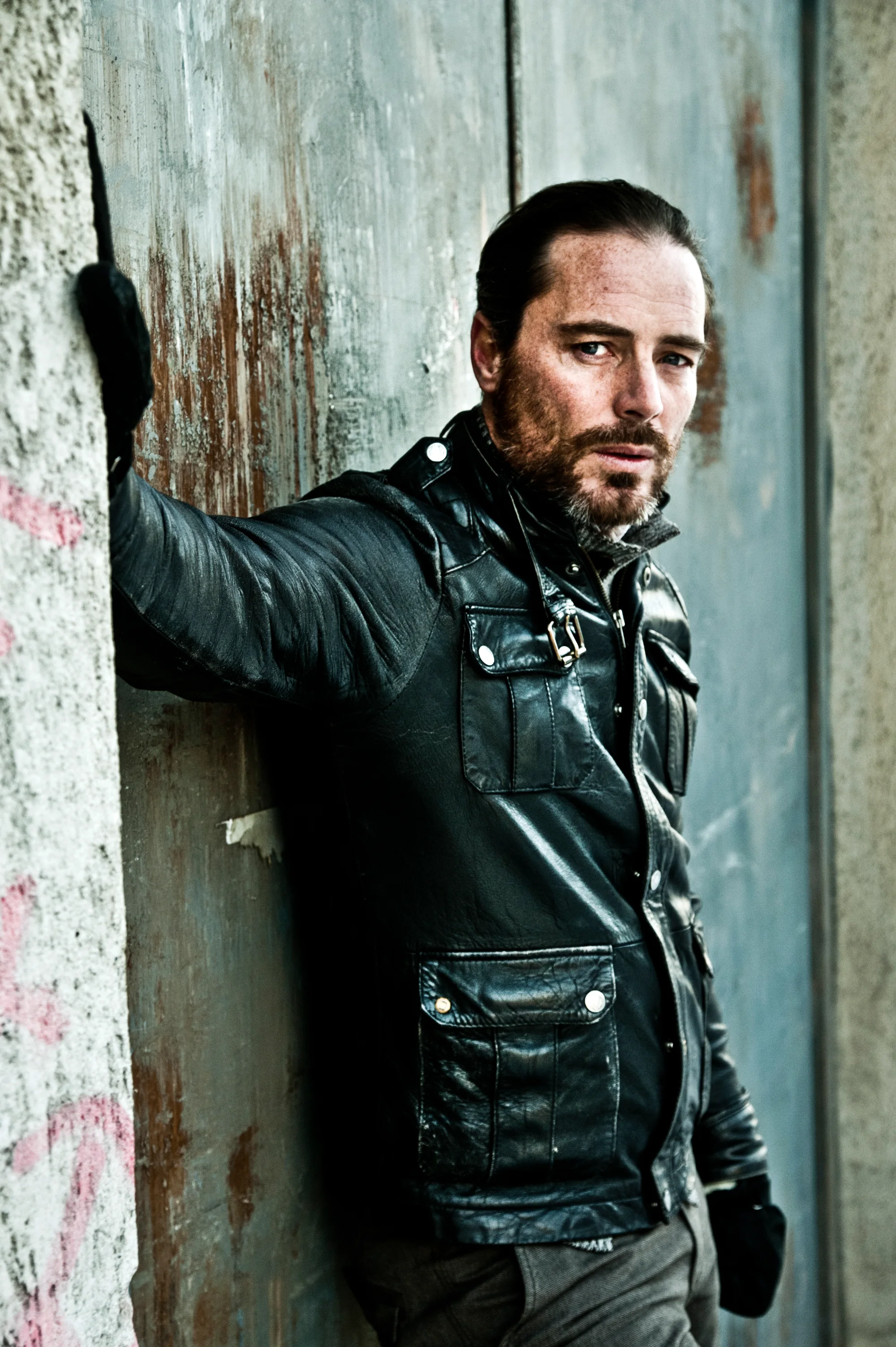 John Friedmann leaning against a weathered wooden door — John Friedmann, actor portrait photography by Janina Laszlo