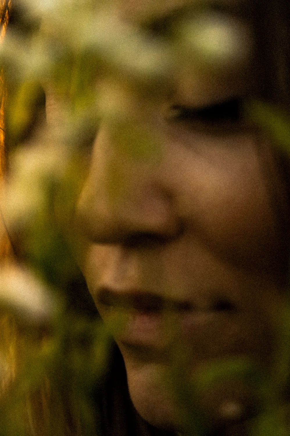 Julia’s face seen through green leaves — Julia, dance portrait photography by Janina Laszlo
