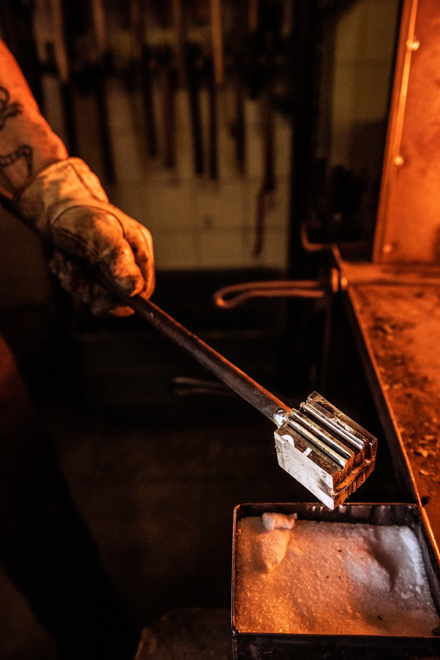 Gloved hand lifting red-hot steel out of the forge with tongs — reportage by Janina Laszlo, photographer in Munich
