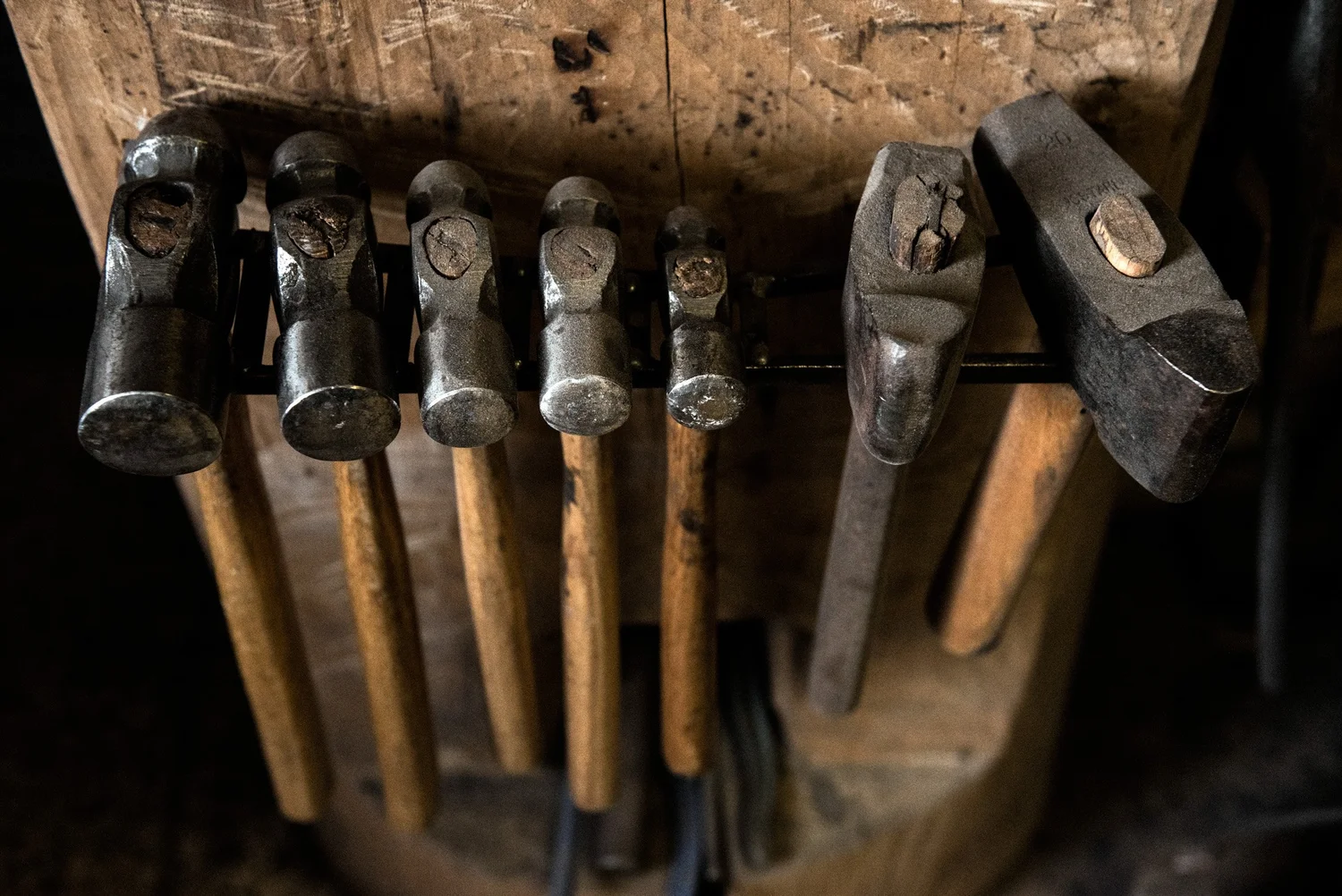 Row of forging hammers hanging on a wooden rack, knife smith's tools — reportage by Janina Laszlo, photographer in Munich