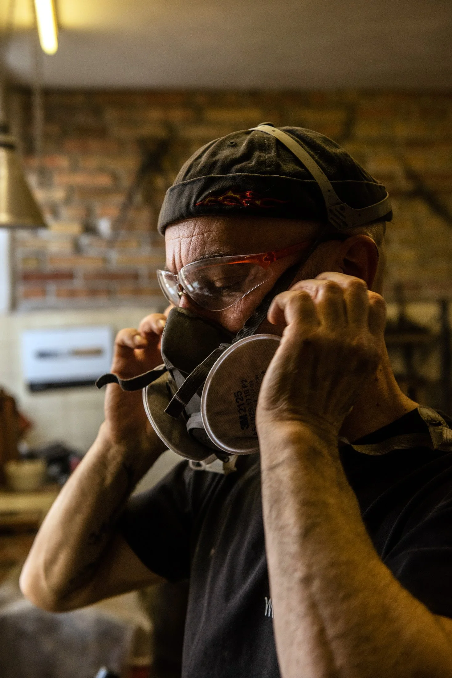 Alfons Bolley putting on his respirator mask before grinding a blade — reportage by Janina Laszlo, photographer in Munich