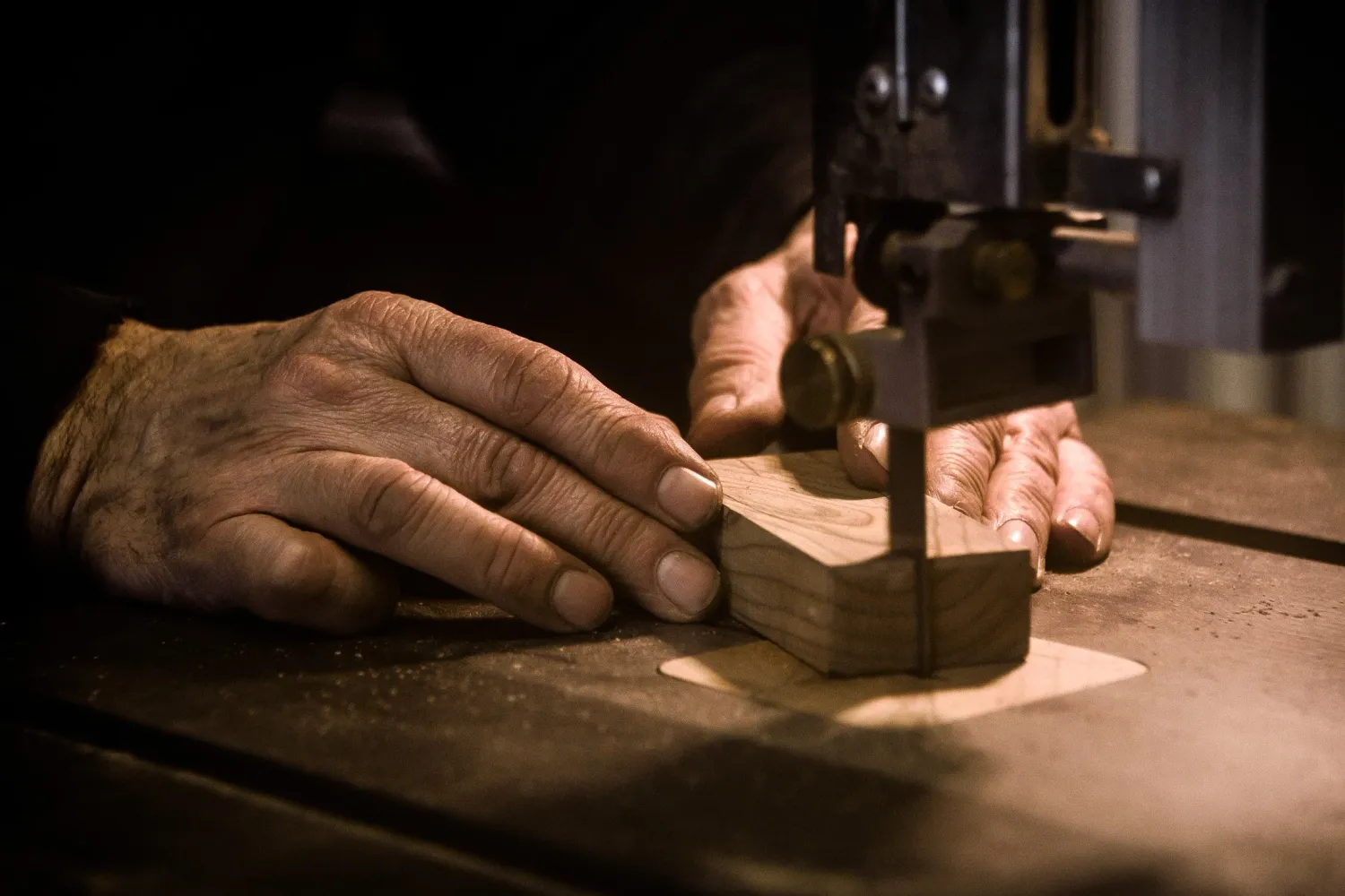 Hands guiding a handle blank through a band saw — knife smith Alfons Bolley — reportage by Janina Laszlo, photographer in Munich