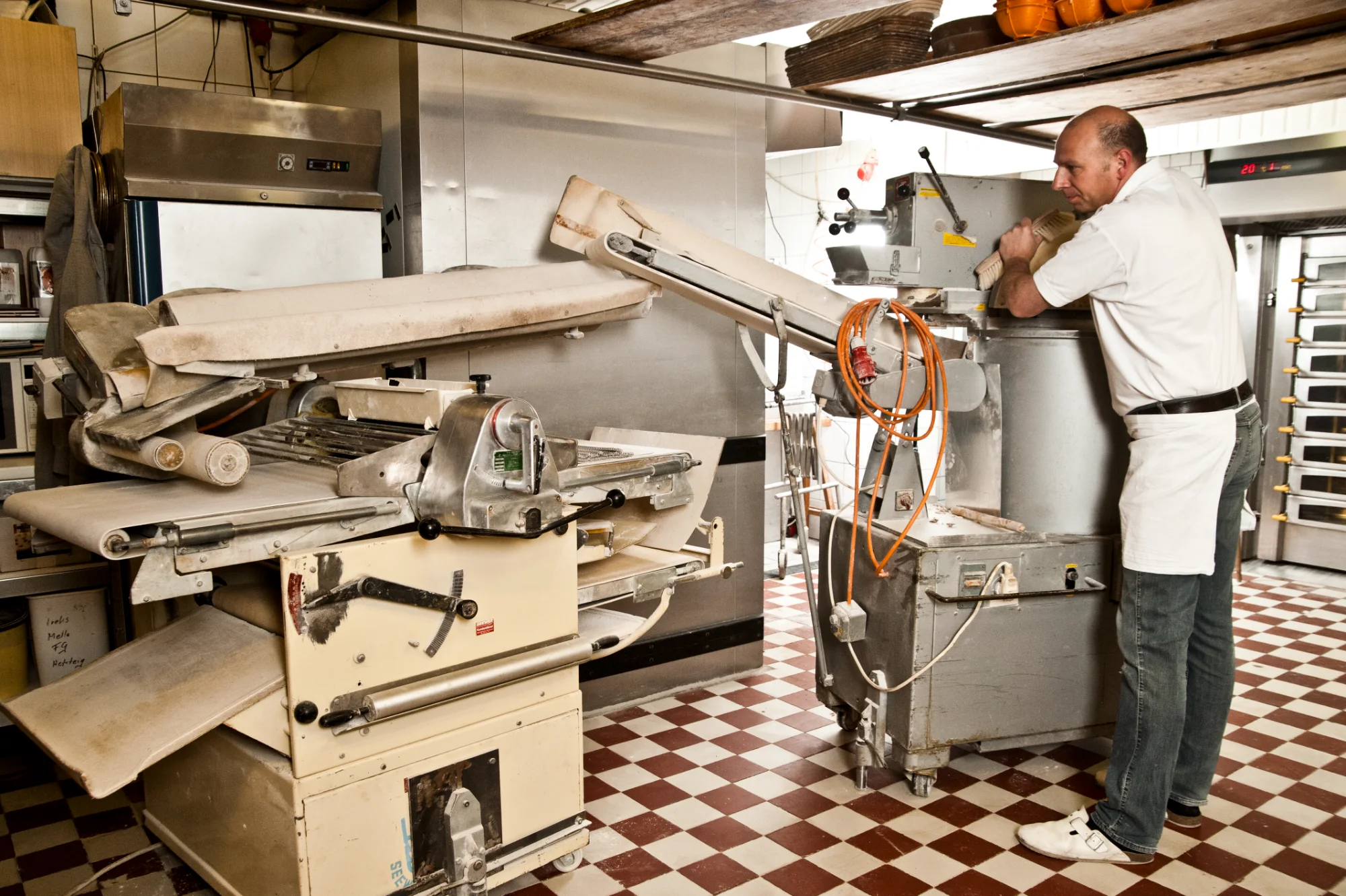 Baker brushing flour from the dough divider beside the dough sheeter — Landbäckerei Zobel, Seefeld, Bavaria, craft bakery photography by Janina Laszlo