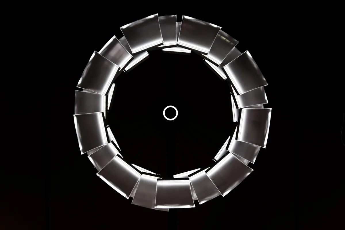 The LC 1.0 chandelier seen from below as a glowing ring of curved light panels against black — LC 1.0 chandelier by Denise M. Hachinger, product and design photography by Janina Laszlo