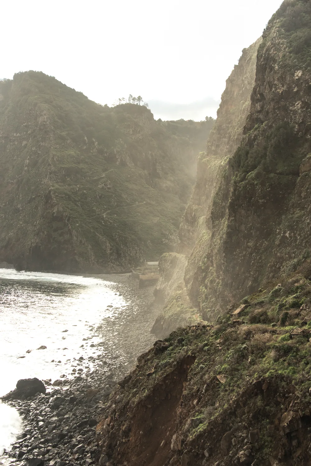 Steep cliffs and a pebble beach veiled in sea spray — Madeira, landscape and travel photography by Janina Laszlo