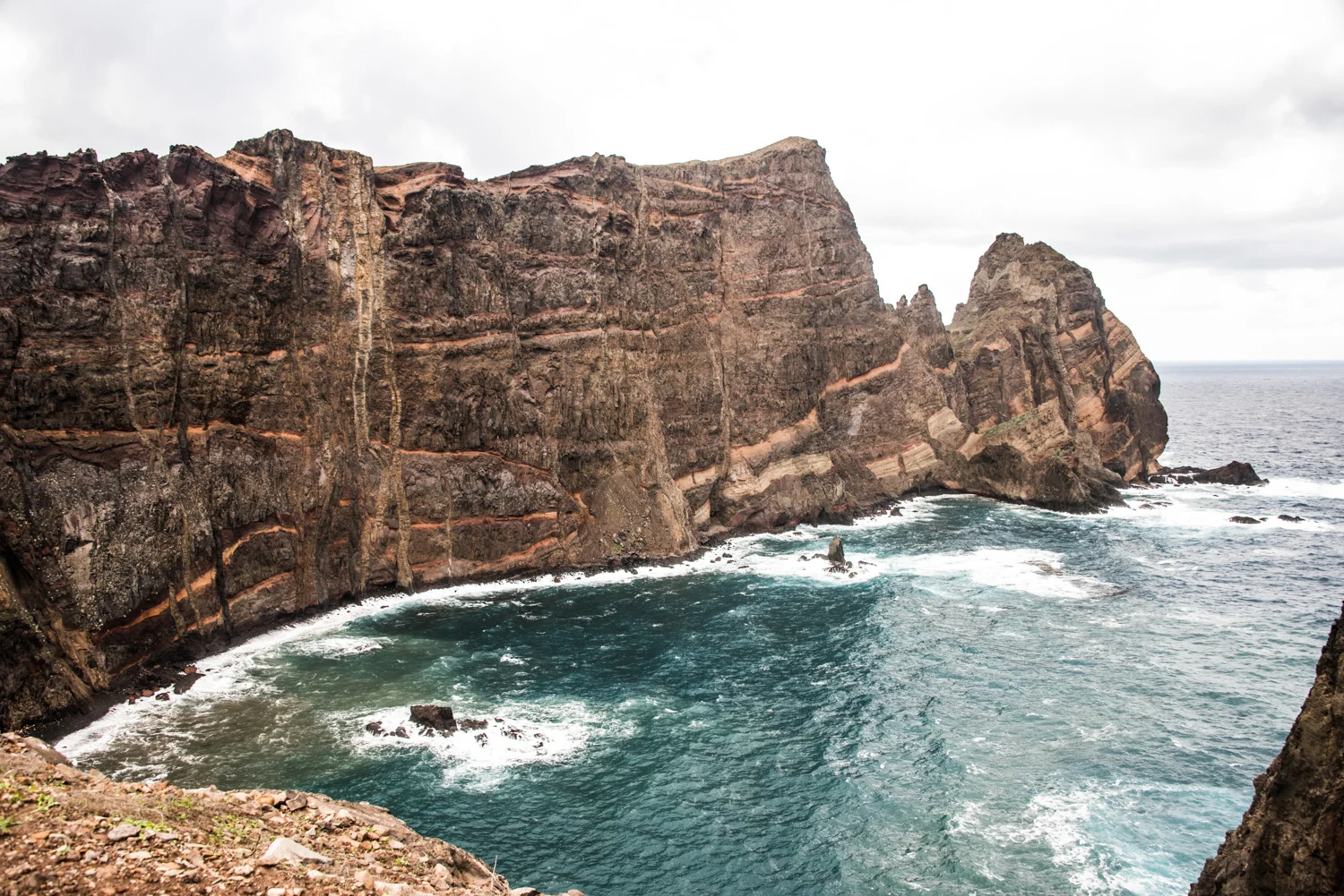 Towering striped volcanic cliffs above a turquoise cove, Ponta de São Lourenço, Madeira — Madeira, travel and landscape photography by Janina Laszlo
