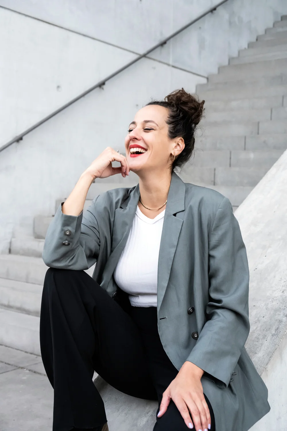 Marie Seidler laughing on concrete steps in a grey blazer — Marie Seidler, mezzo-soprano, opera portrait photography by Janina Laszlo