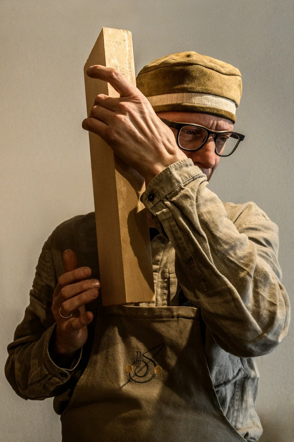 Martin Schleske holding a tonewood block to his ear to listen to the wood — Martin Schleske, master violin maker, editorial portrait and documentary photography by Janina Laszlo, Landsberg am Lech