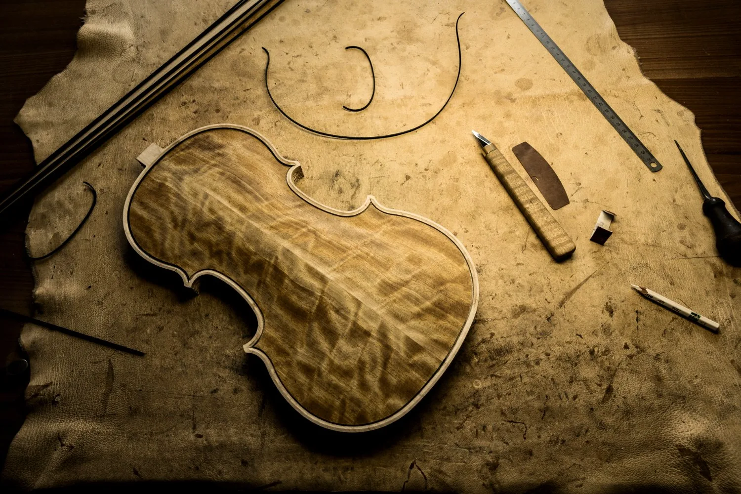 Hand-carved violin top on leather surrounded by tools — Martin Schleske, master violin maker, editorial portrait and documentary photography by Janina Laszlo, Landsberg am Lech