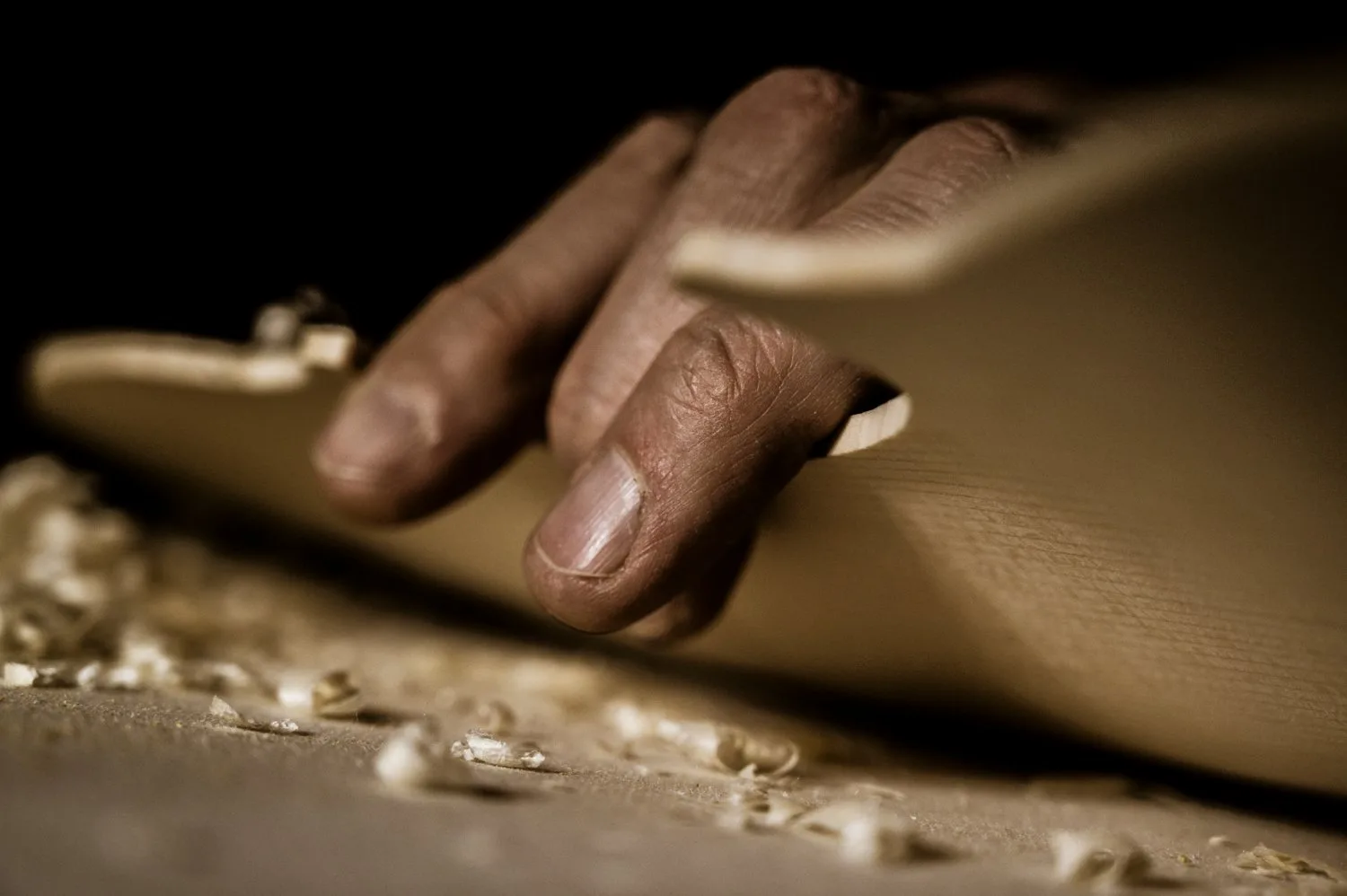 Hand gliding over planed spruce with curled shavings — Martin Schleske, master violin maker, editorial portrait and documentary photography by Janina Laszlo, Landsberg am Lech