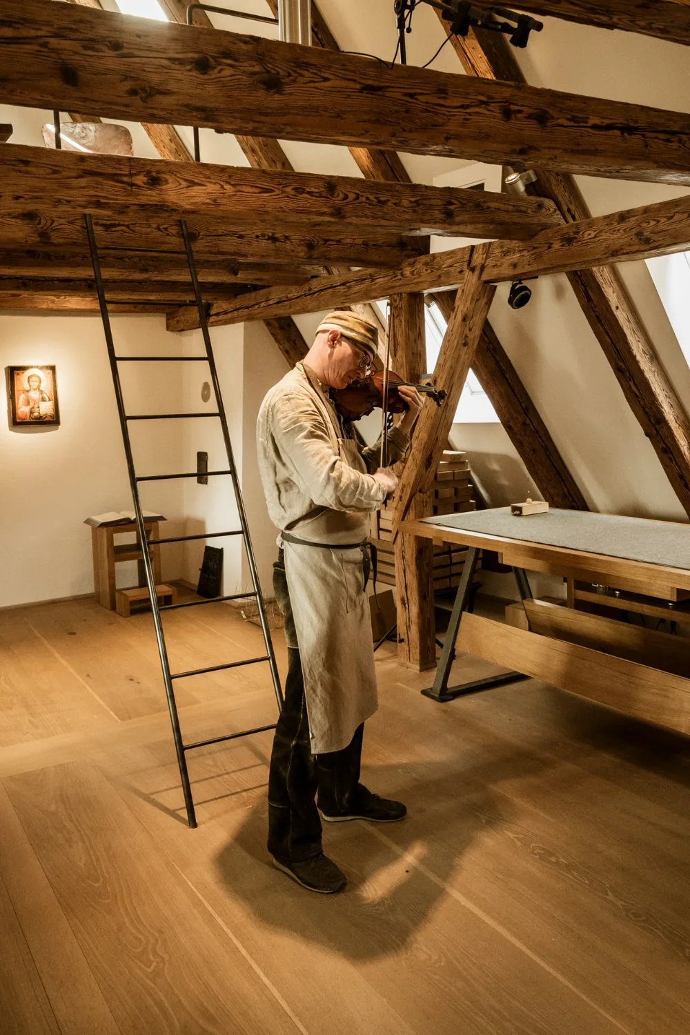 Martin Schleske standing in his attic workshop beneath wooden beams — Martin Schleske, master violin maker, editorial portrait and documentary photography by Janina Laszlo, Landsberg am Lech