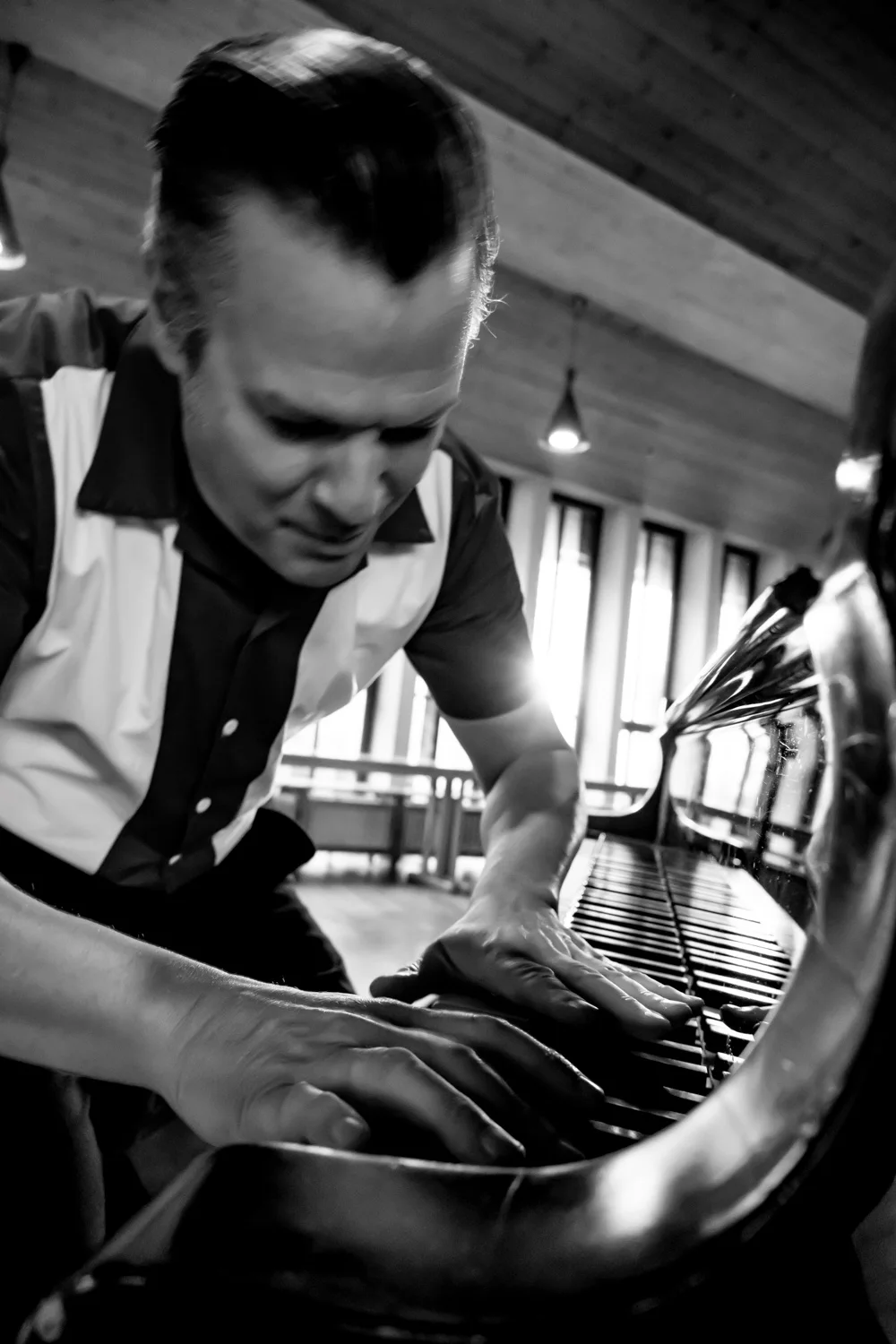 Matthias Heiligensetzer bent over the keys in a bowling shirt, black-and-white — Matthias Heiligensetzer, pianist & entertainer, musician portrait photography by Janina Laszlo, Munich