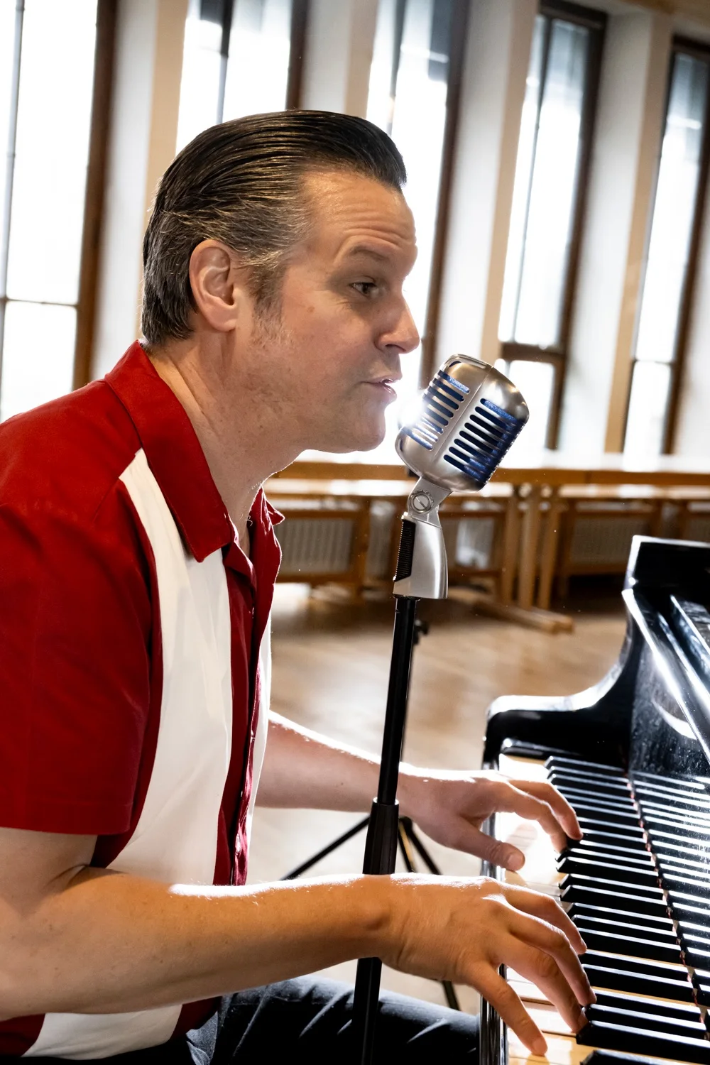 Matthias Heiligensetzer in profile singing into a vintage microphone while playing piano — Matthias Heiligensetzer, pianist & entertainer, musician portrait photography by Janina Laszlo, Munich