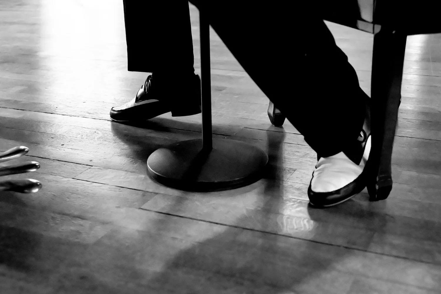 Two-tone shoes beside the microphone stand on a parquet floor, black-and-white — Matthias Heiligensetzer, pianist & entertainer, musician portrait photography by Janina Laszlo, Munich