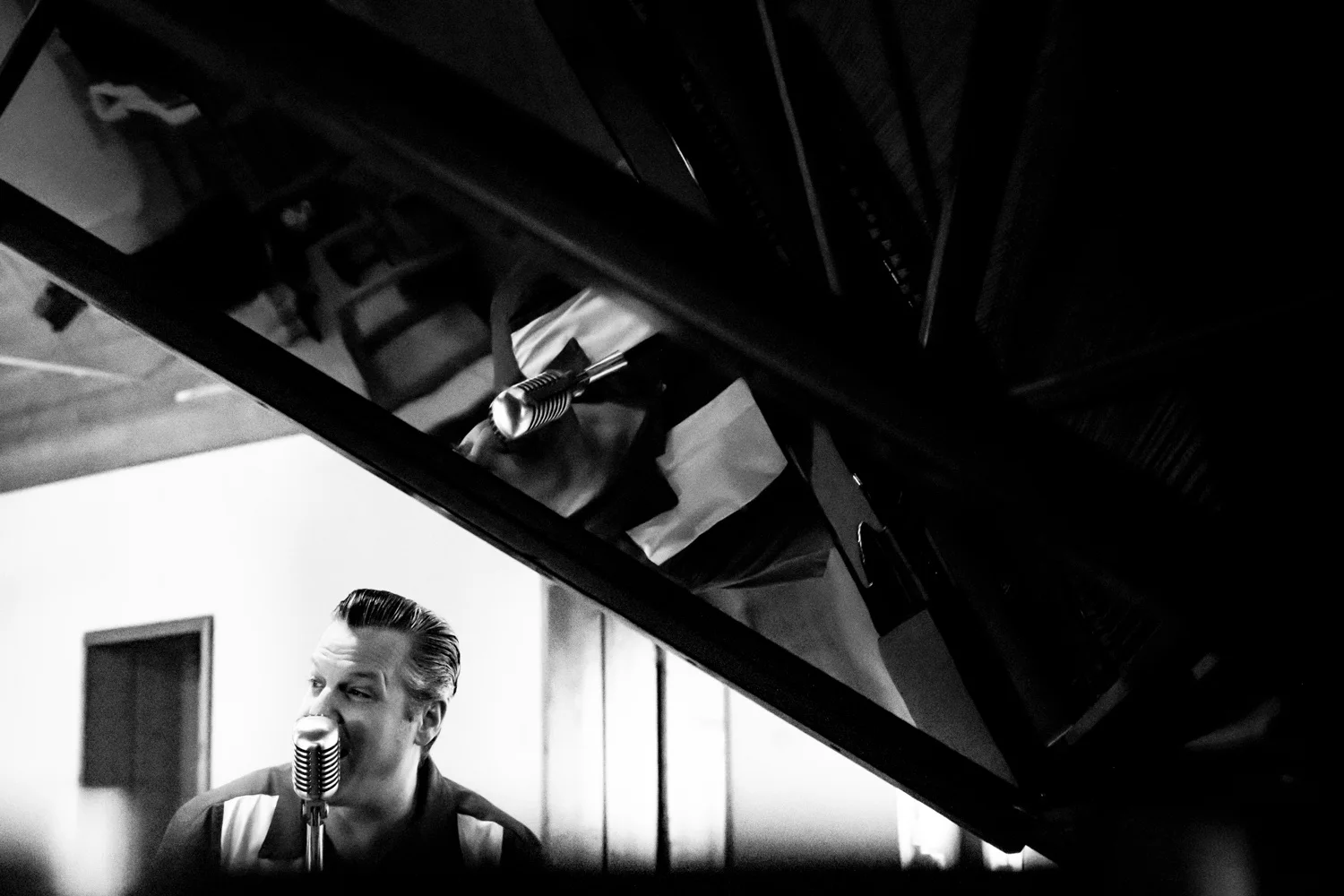 Matthias Heiligensetzer singing beneath the open lid of a grand piano, black-and-white — Matthias Heiligensetzer, pianist & entertainer, musician portrait photography by Janina Laszlo, Munich