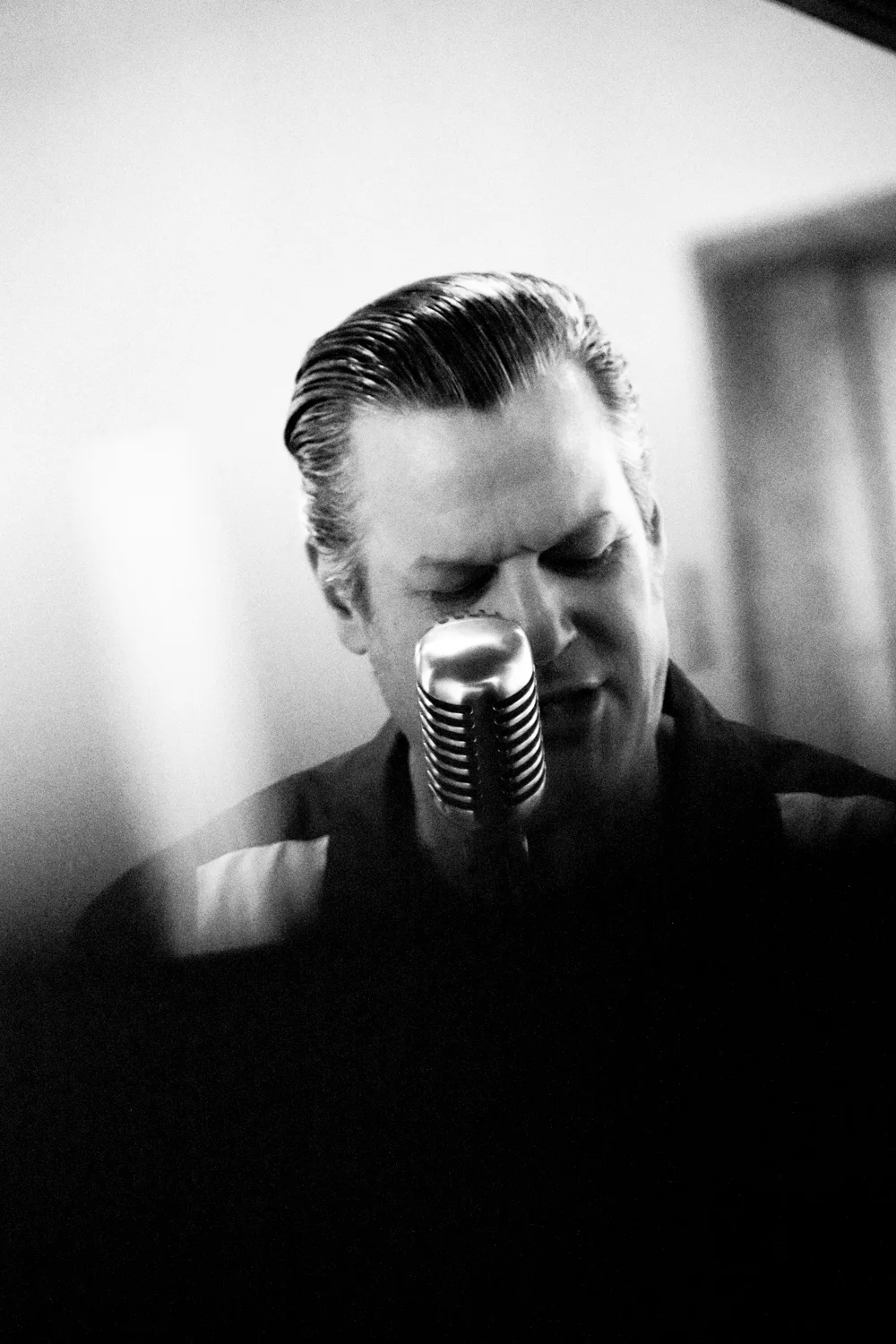 Matthias Heiligensetzer singing softly into a vintage microphone, black-and-white — Matthias Heiligensetzer, pianist & entertainer, musician portrait photography by Janina Laszlo, Munich