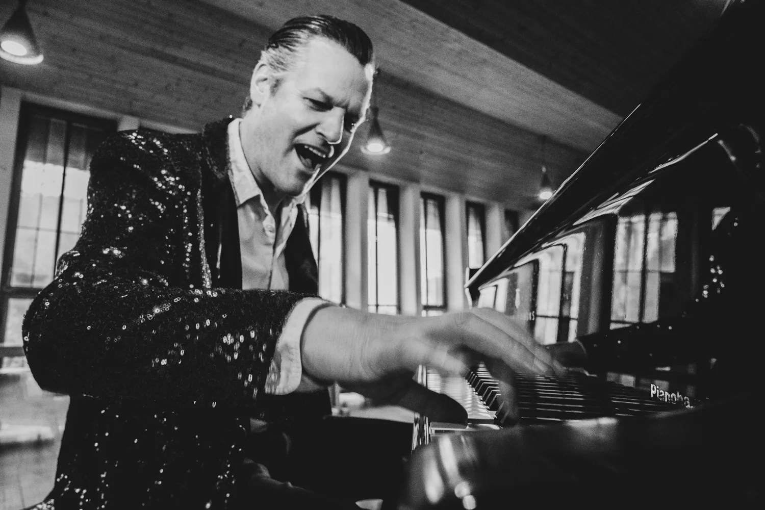 Matthias Heiligensetzer laughing at the piano in a sequin jacket, black-and-white — Matthias Heiligensetzer, pianist & entertainer, musician portrait photography by Janina Laszlo, Munich