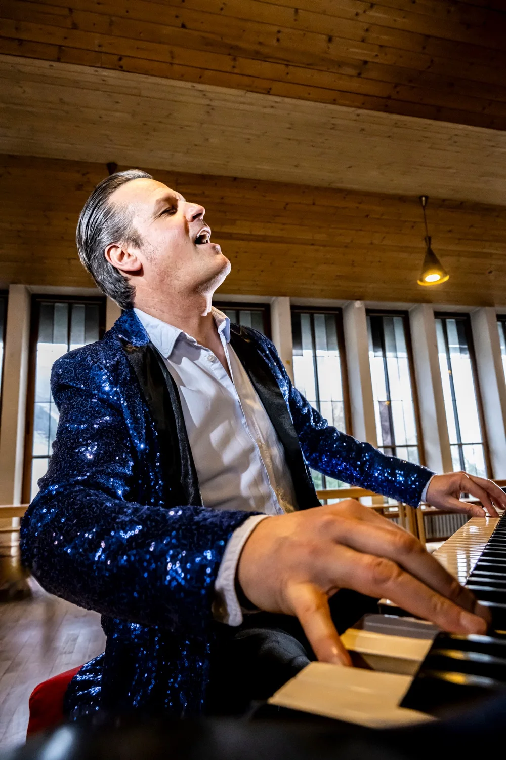 Matthias Heiligensetzer singing with his head thrown back at the piano in a blue sequin jacket — Matthias Heiligensetzer, pianist & entertainer, musician portrait photography by Janina Laszlo, Munich