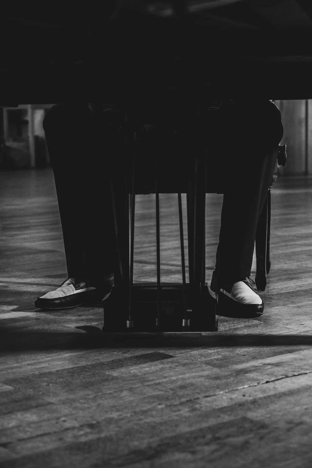 Two-tone shoes and piano pedals beneath a grand piano, black-and-white — Matthias Heiligensetzer, pianist & entertainer, musician portrait photography by Janina Laszlo, Munich