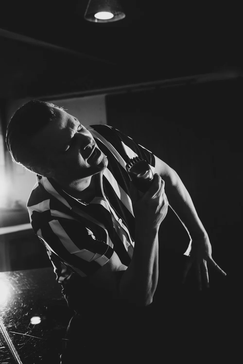 Matthias Heiligensetzer in a striped shirt singing in dramatic backlight, black-and-white — Matthias Heiligensetzer, pianist & entertainer, musician portrait photography by Janina Laszlo, Munich
