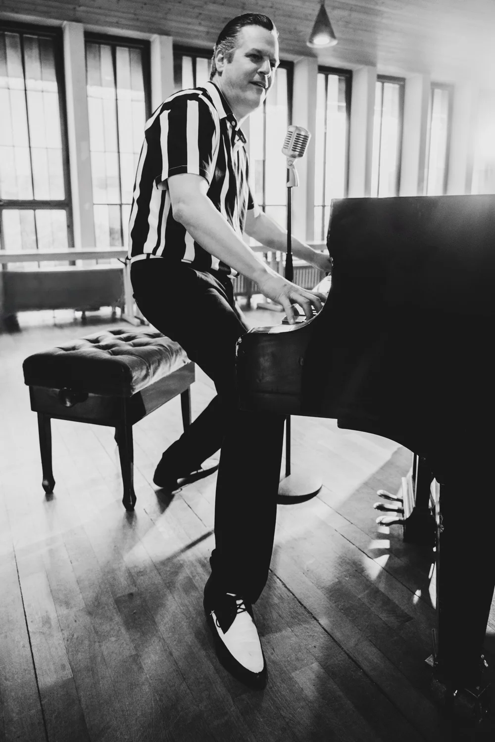Matthias Heiligensetzer in a striped shirt and two-tone shoes playing piano standing, black-and-white — Matthias Heiligensetzer, pianist & entertainer, musician portrait photography by Janina Laszlo, Munich