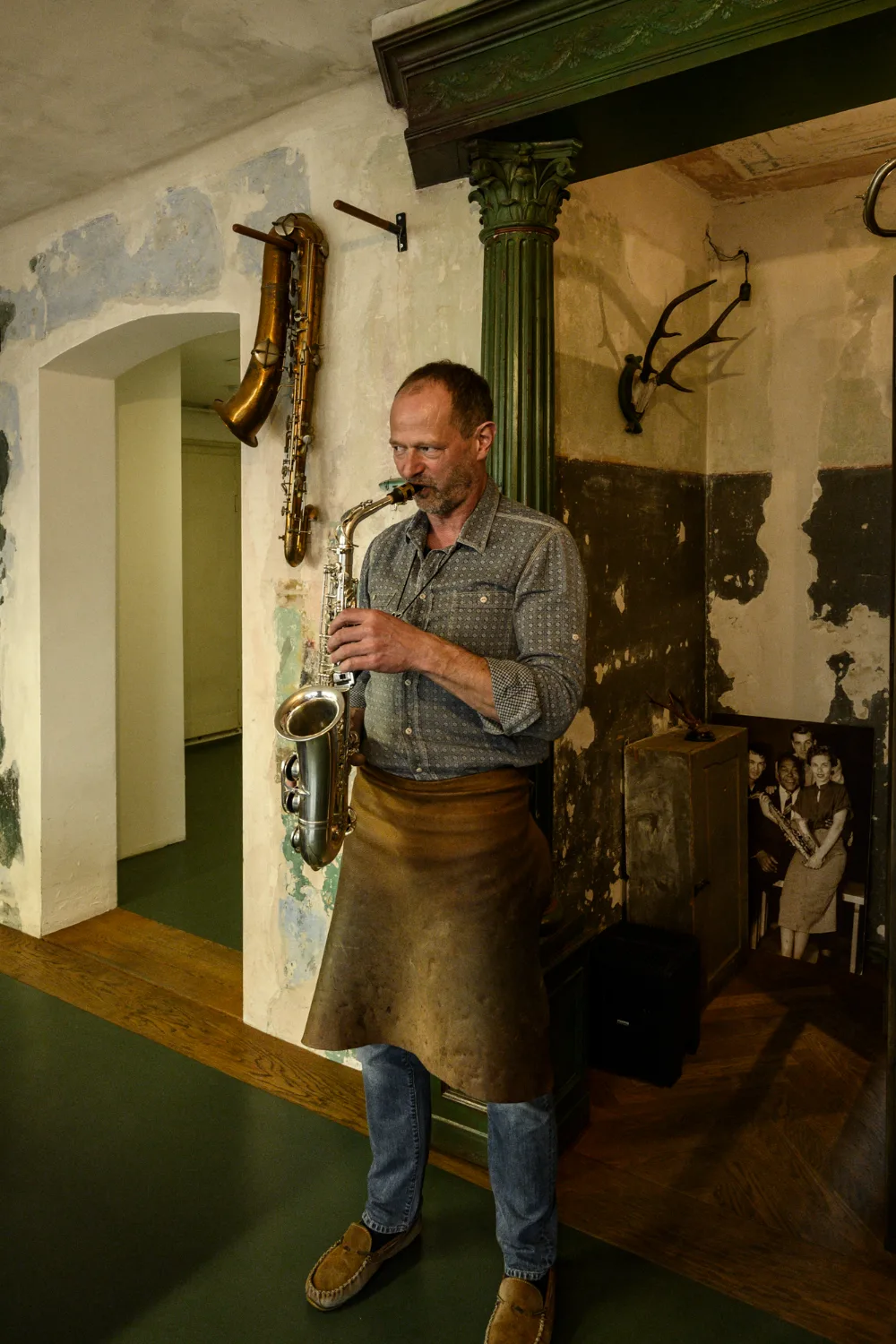 Max Frei playing a silver alto saxophone beneath a green column — Max Frei, saxophone workshop in Icking near Munich, corporate portraits and editorial photography by Janina Laszlo
